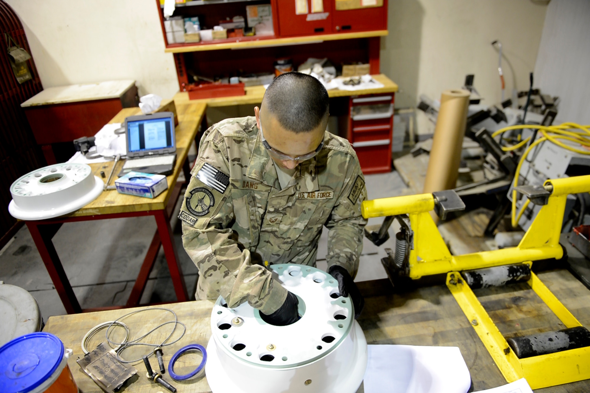 Staff Sgt. John Dang, 455th Expeditionary Maintenance Squadron crash recovery team member, removes nuts and bolts from a wheel before a proper assembly, May 19, 2014 at Bagram Airfield, Afghanistan.  As part of the wheel and tire shop, Dang provides serviceable tires for A-10 Thunderbolt IIs and F-16 Fighting Falcons, the shop repairs an average of 48 wheels per month. Dang is deployed from Whiteman Air Force Base, Mo. and a native of Overland Park, Kan.  (U.S. Air Force photo by Staff Sgt. Evelyn Chavez/Released)