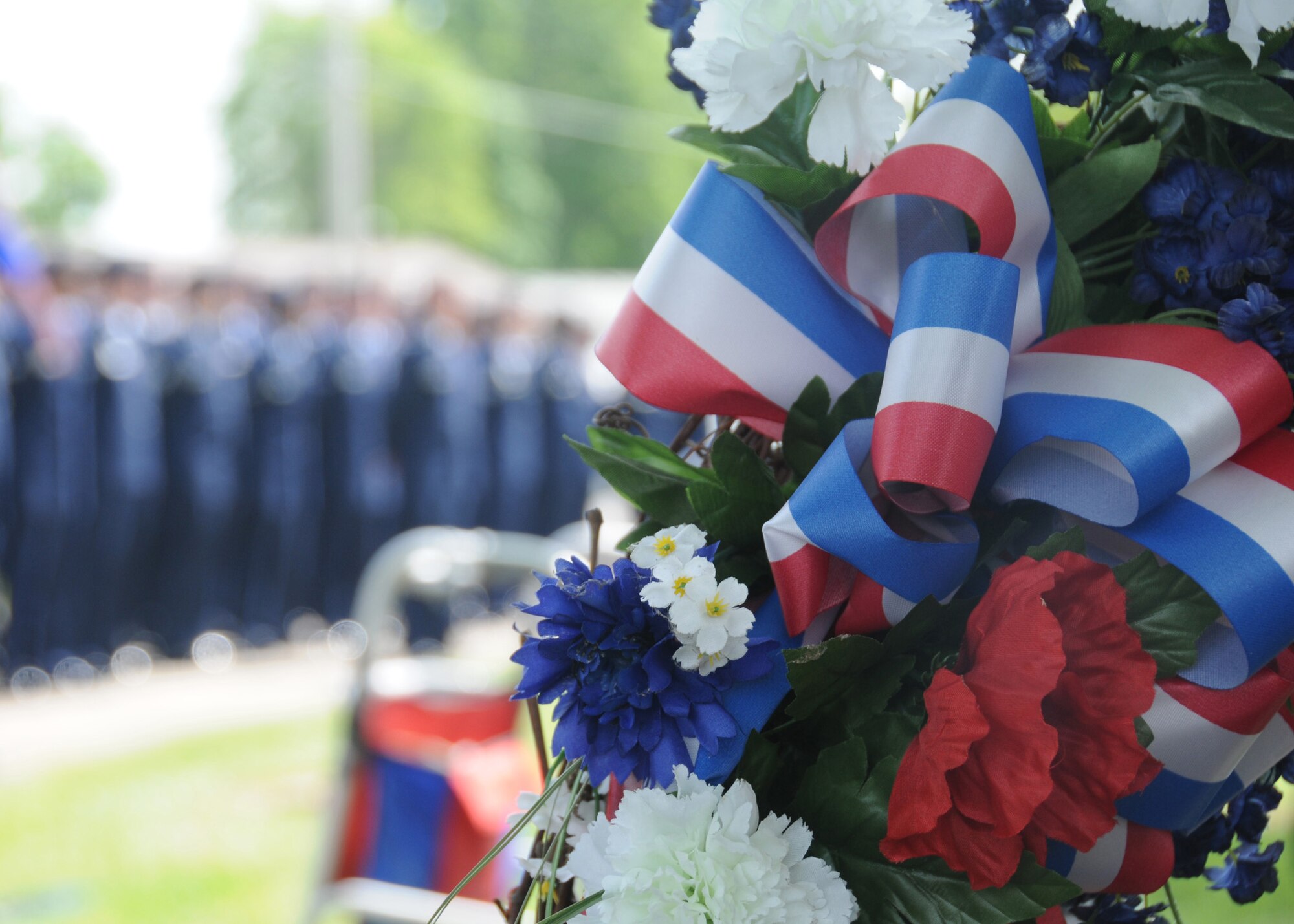 Members of 2nd Lt. George A. Whiteman's family laid the wreath at the tombstone of their fallen uncle May 17, 2014, at Memorial Park Cemetery in Sedalia, Missouri. Airmen of the 509th Security Forces Squadron, Whiteman Air Force Base, Missouri., stand at attention in the background as the invocation was read before the ceremony. (U.S. Air National Guard photo by Senior Airman Nathan Dampf/Released)
