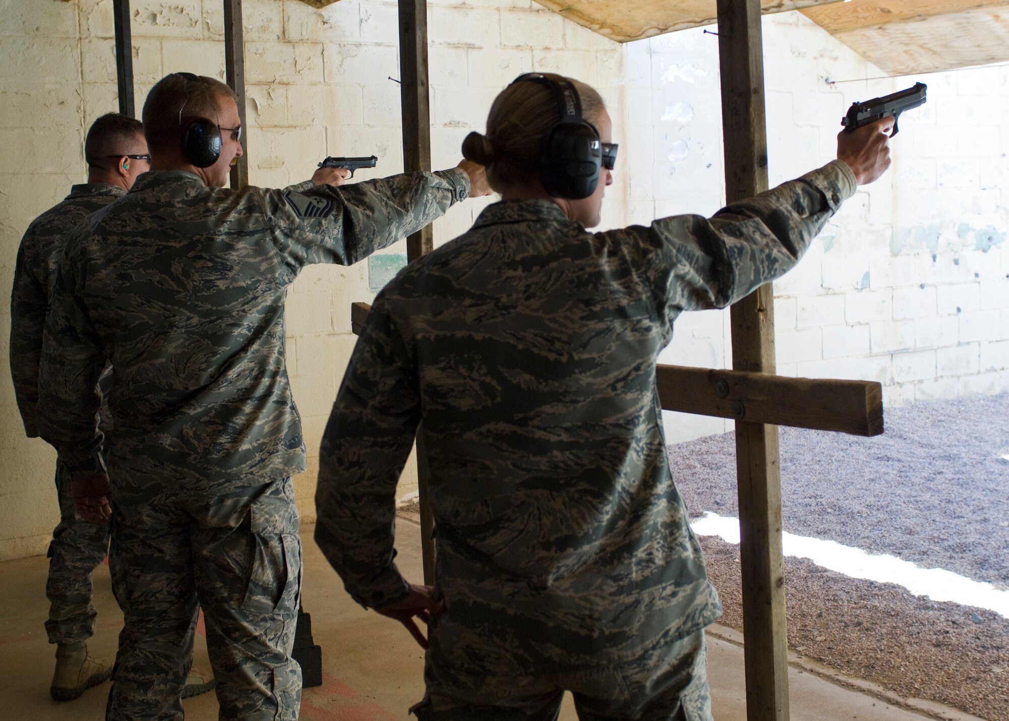 From left, U.S. Air Force Master Sgt. Hywel Wilson and Master Sgt. Todd Duquette Sr., both 7th Security Forces Squadron, and Maj. Sarah Babbitt, 7th SFS commander, shoot M9 Beretta pistols May 14, 2014, at Dyess Air Force Base, Texas. The firing competition was held during National Police Week to honor fallen law enforcement officers and fellow Airmen who have given their lives in the line of duty. (U.S. Air Force photo by Airman 1st Class Kylsee Wisseman/Released) 