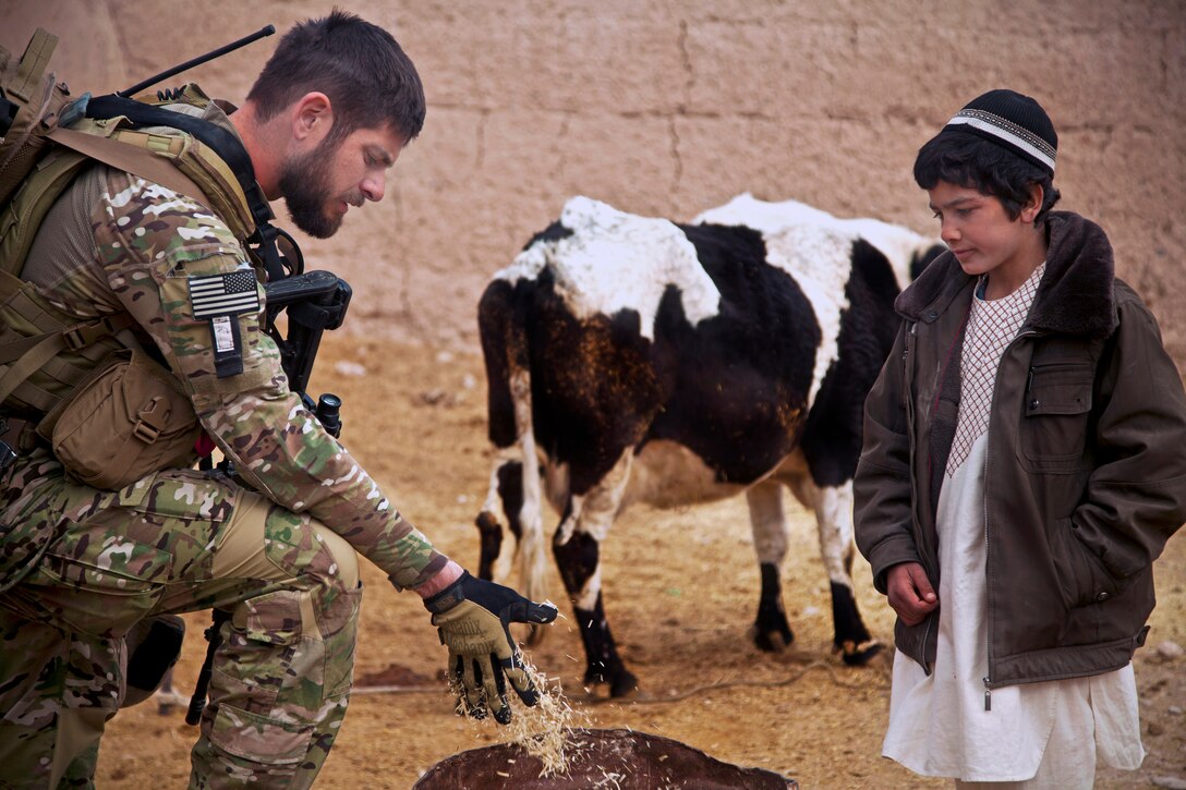 A coalition force member talks to a young villager about what to feed cattle during a patrol of Afghanistan's Farah province, Dec. 15, 2012.  
