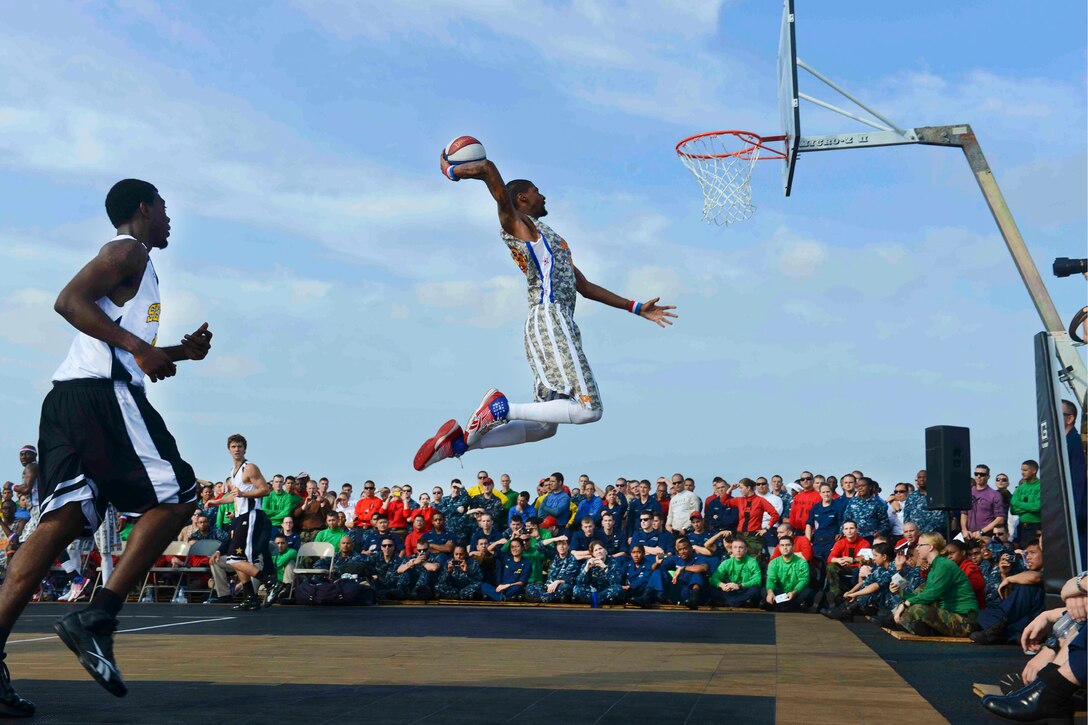 Quade "Quake" Milum, a member of the Harlem Globetrotters, dunks the ball during an exhibition game on the flight deck of the aircraft carrier USS John C. Stennis under way in the Arabian Sea, Dec. 7, 2012.  
