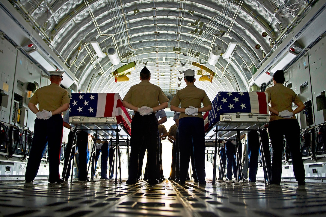 Service members stand at parade rest next to flag-draped transfer cases during the U.S. Joint POW/MIA Accounting Command Arrival Ceremony on Joint Base Pearl Harbor-Hickam, Nov. 30, 2012, in honor of fallen U.S. personnel whose identities remain unknown.  
