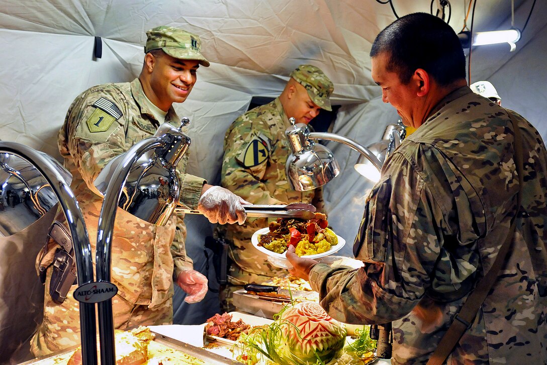 U.S. Army Capt. Jefferson Mason, left, serves Thanksgiving dinner to a soldier on Joint Combat Outpost Mushan, Afghanistan, Nov. 22, 2012. Mason commands the 2nd Infantry Division's 38th Engineer Company, 4th Stryker Brigade Combat Team.  
