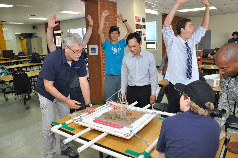 Students at Seoul American Middle School react as Doug Bliss (left), chief of the geotechnical and environmental engineering branch, and Son Ha (center), engineering division design branch chief, test the stability of a student made tower at Seoul American Middle School May 19. 