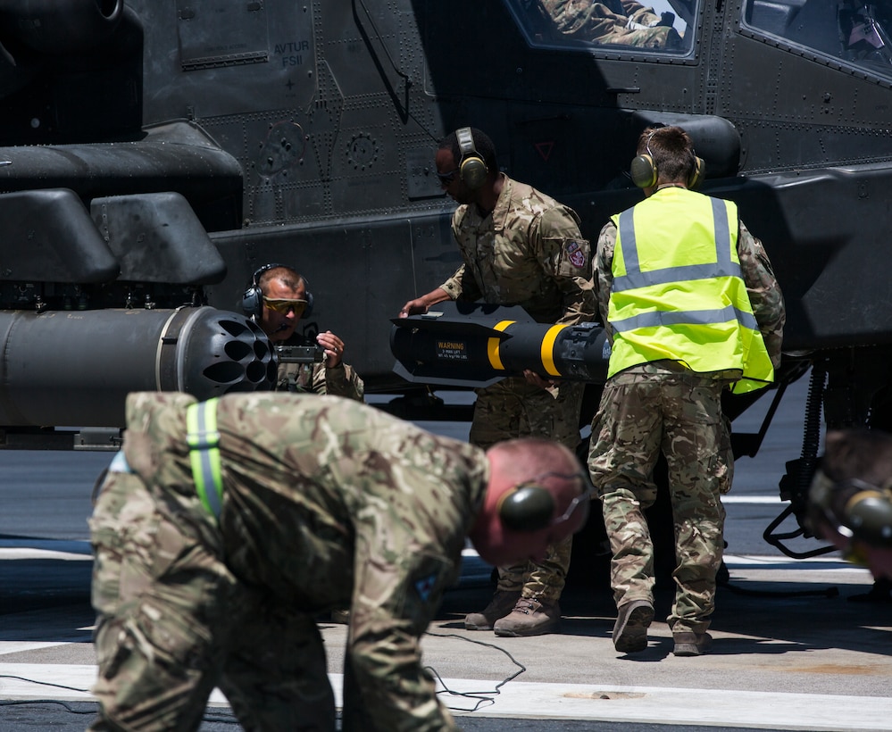 United Kingdom soldiers load an AGM-114 Hellfire missile onto an AH-64 Apache helicopter on the flight line of Gila Bend Air Force Auxiliary Field, Gila Bend, Ariz., May 4. After being outfitted with ordnance, the aircraft set out to conduct a live-fire exercise in coordination with Marine Corps joint terminal attack controllers.