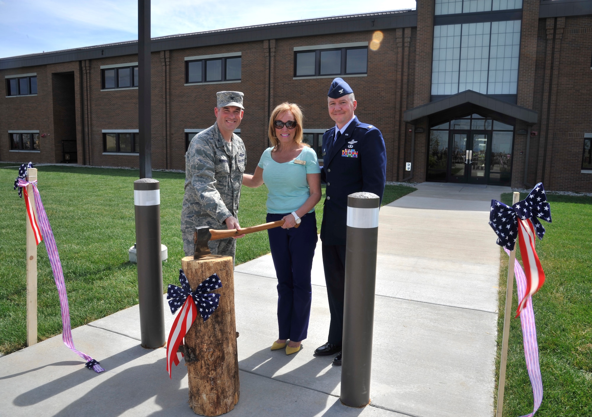 (From left to right) Col. Brian Newberry, Lisa Chapman-Rosa and Col. William Thomas pose for a photo after the ceremonial ribbon cutting in front of the new 336th Training Group headquarters building at Fairchild Air Force Base, Wash., May 21, 2014. Newberry is the 92nd Air Refueling Wing commander, Chapman-Rosa is the president/owner of Total Site Services and Thomas is the 336th TRG commander. (U.S. Air Force photo by Senior Airman Mary O'Dell/Released)