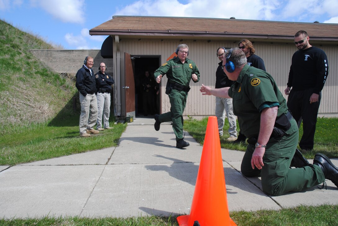 Grand Forks Sector Chief Border Patrol Agent Austin Skero, tags Division Chief Andy Althoff, during the 2014 Police Week Commanders’ Shoot held May 15, 2014, at the firing range on Grand Forks Air Force Base, N.D. The Border Patrol Agents were two of several members from the Department of Homeland Security that participated in the stress shoot. The shooting competition required the second and third shooters to sprint and do push-ups after being tagged by a teammate.  (U.S. Air Force photo/Staff Sgt. Luis Loza Gutierrez) 
