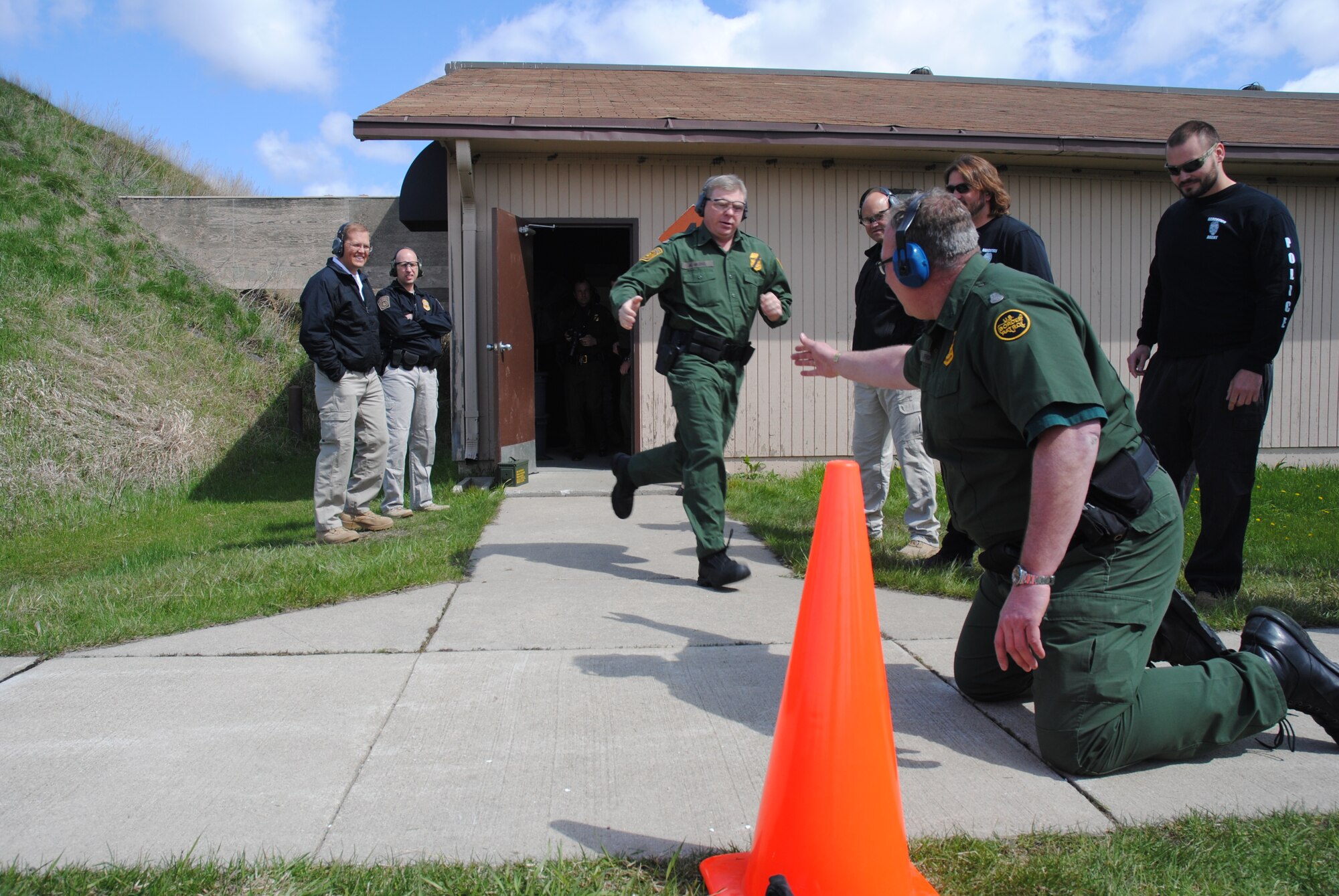 Grand Forks Sector Chief Border Patrol Agent Austin Skero, tags Division Chief Andy Althoff, during the 2014 Police Week Commanders’ Shoot held May 15, 2014, at the firing range on Grand Forks Air Force Base, N.D. The Border Patrol Agents were two of several members from the Department of Homeland Security that participated in the stress shoot. The shooting competition required the second and third shooters to sprint and do push-ups after being tagged by a teammate.  (U.S. Air Force photo/Staff Sgt. Luis Loza Gutierrez) 
