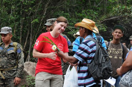 A Honduran man gives U. S. Air National Guard Capt. Sherri Pierce flowers after receiving a bag of food and supplies from her.  More than 120 members of Joint Task Force-Bravo, with the support of Joint Task Force-Bravo's Joint Security Forces and the Honduran military, completed a volunteer seven mile round trip hike to deliver 2,500 pounds of food and supplies to families in need in the mountain village of El Tamarindo outside Comayagua, Honduras, May 17, 2014.  The effort was part of the 54th Joint Task Force-Bravo Chapel Hike, a venerable tradition during which Task Force members donate money to purchase food and supplies and then carry those supplies on a hike through the mountains to deliver them to local, underserviced communities.  (Photo by U. S. Air National Guard Capt. Steven Stubbs)
