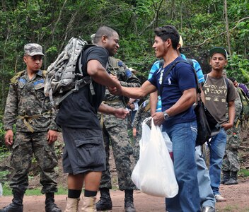 A Honduran man and a Joint Task Force-Bravo member shake hands after receiving a bag of food and supplies.  More than 120 members of Joint Task Force-Bravo, with the support of Joint Task Force-Bravo's Joint Security Forces and the Honduran military, completed a volunteer seven mile round trip hike to deliver 2,500 pounds of food and supplies to families in need in the mountain village of El Tamarindo outside Comayagua, Honduras, May 17, 2014.  The effort was part of the 54th Joint Task Force-Bravo Chapel Hike, a venerable tradition during which Task Force members donate money to purchase food and supplies and then carry those supplies on a hike through the mountains to deliver them to local, underserviced communities.  (Photo by Ana Fonseca)
