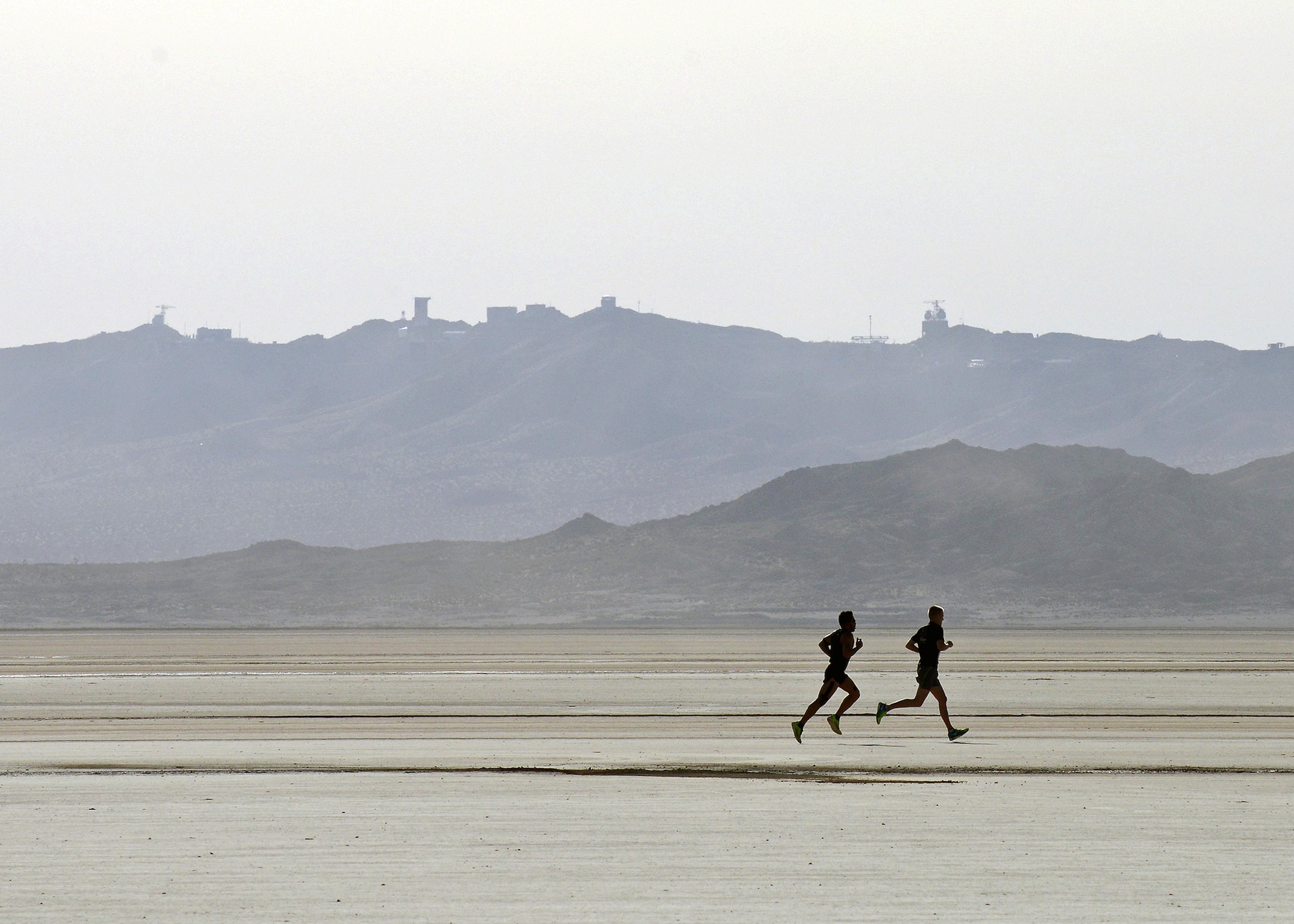 The sihouette of two runners on the Rogers Dry Lakebed can be seen in the distance as the near the half-way point during the 2014 Edwards Inaugural "Run with History" Half Marathon on May 17. Of the 500 runners who registered, 462 showed up to run and the event had approximately 200 spectators. (U.S. Air Force photo by Jet Fabara)