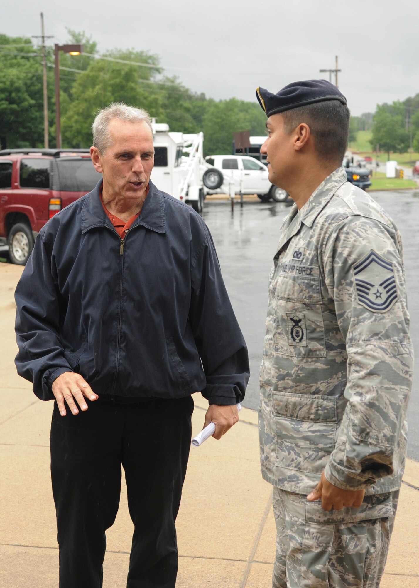Chris Schack, 19th Airlift Wing Protocol deputy chief, speaks to Senior Master Sgt. Carlos Rosa, 19th Security Forces Squadron operations superintendent May 14, 2014, at the front gate of Little Rock Air Force Base, Ark. Security Forces is one of the many organizations that protocol works with to ensure events run smoothly. (U.S. Air Force photo by Airman 1st Class Harry Brexel)