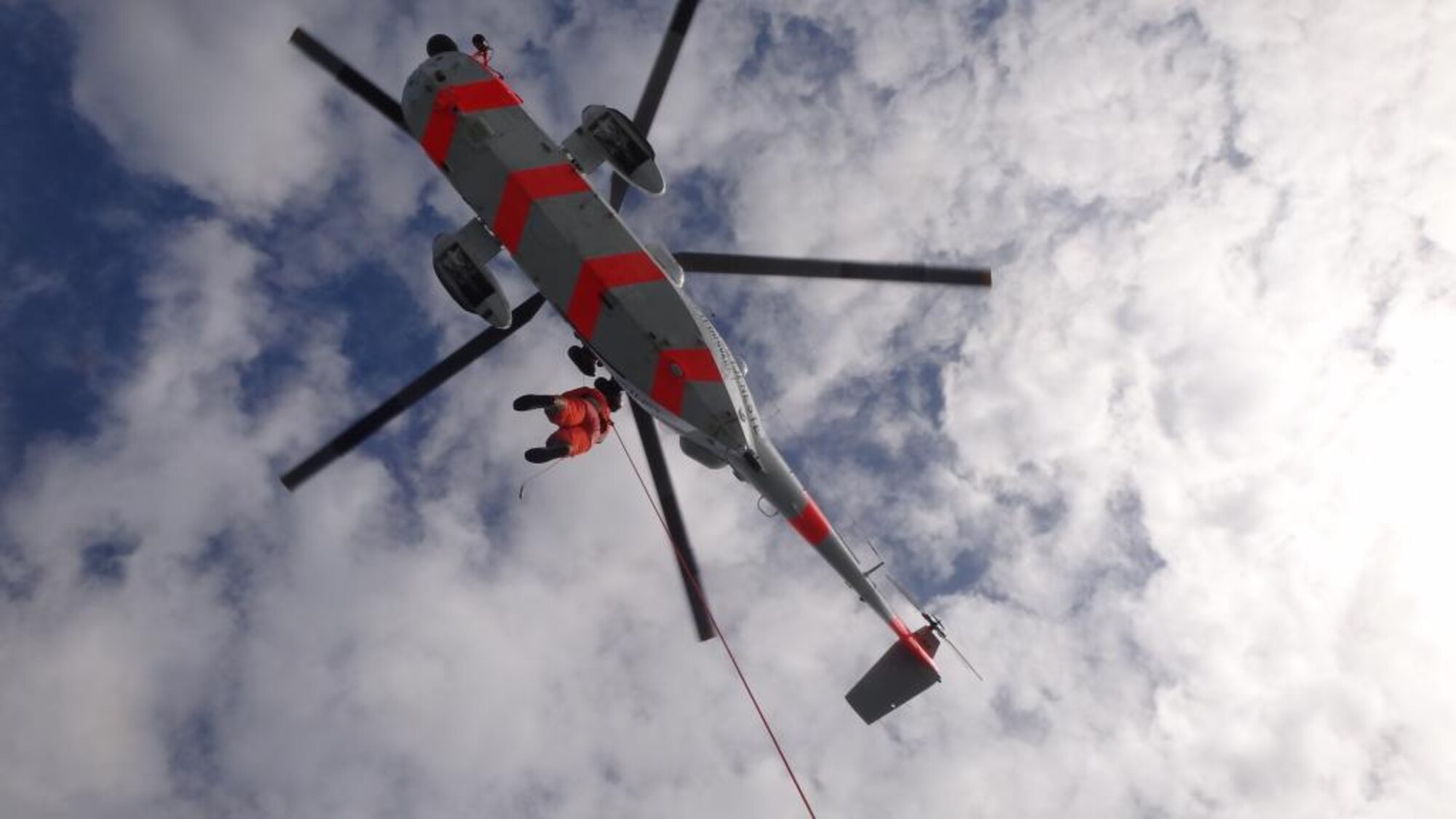 Staff Sgt. Jennifer Thaxton, 426th Air Base Squadron custodian of postal effects, dangles from a Royal Norwegian Air Force helicopter during an exercise in the North Sea May 13, 2014. Thaxton and three other Airmen from the 426th ABS volunteered to support training and certification efforts of the RNAF 330th Rescue Squadron. (Courtesy photo/Released)