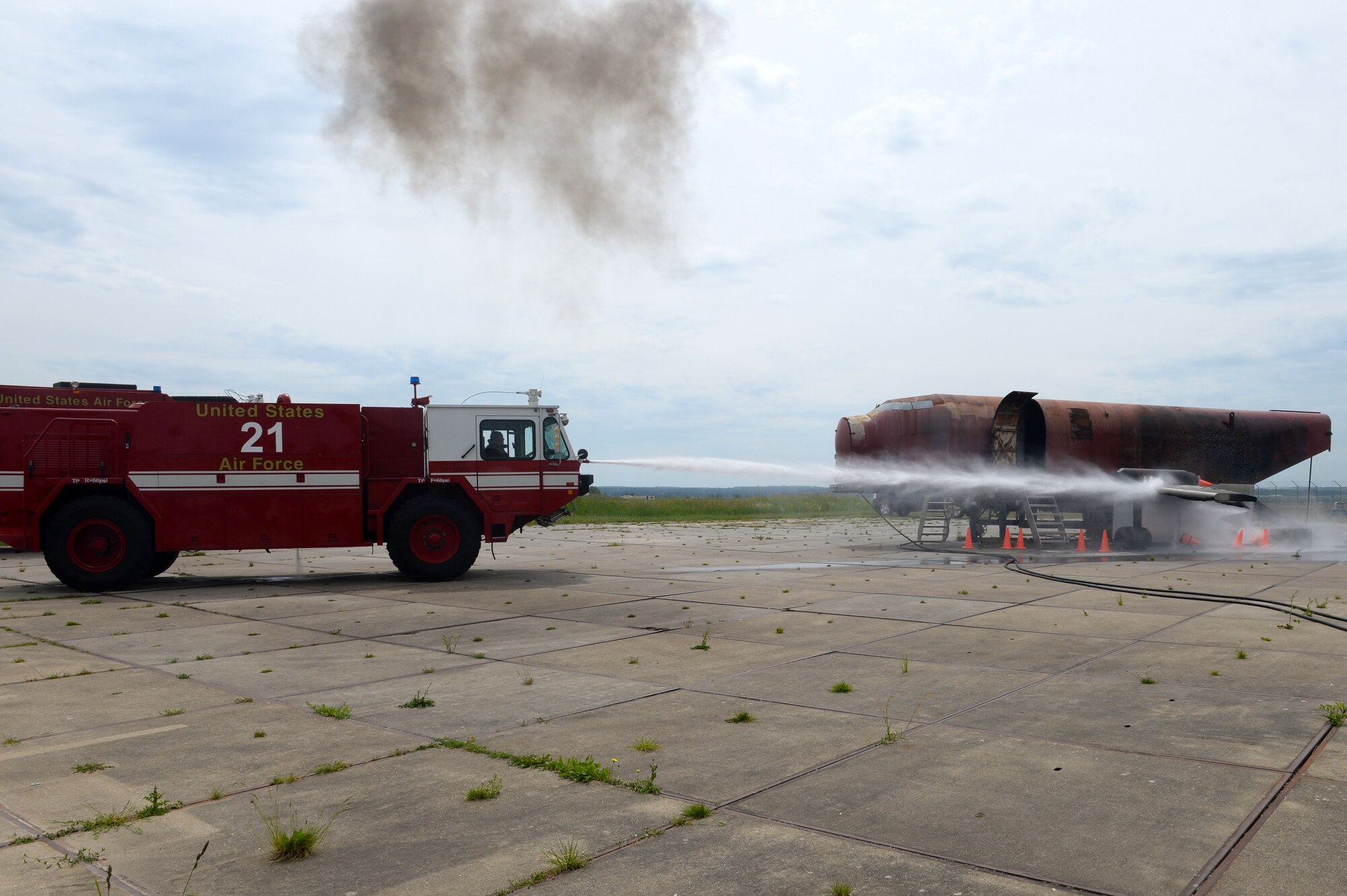Firefighters from the 52nd Civil Engineer Squadron Fire Emergency Services Flight spray down an aircraft simulator fire during an exercise at Spangdahlem Air Base, Germany, May 21, 2014. These Airmen exercise different fire emergency situations every day to keep their skills sharp. (U.S. Air Force photo by Senior Airman Alexis Siekert/Released)