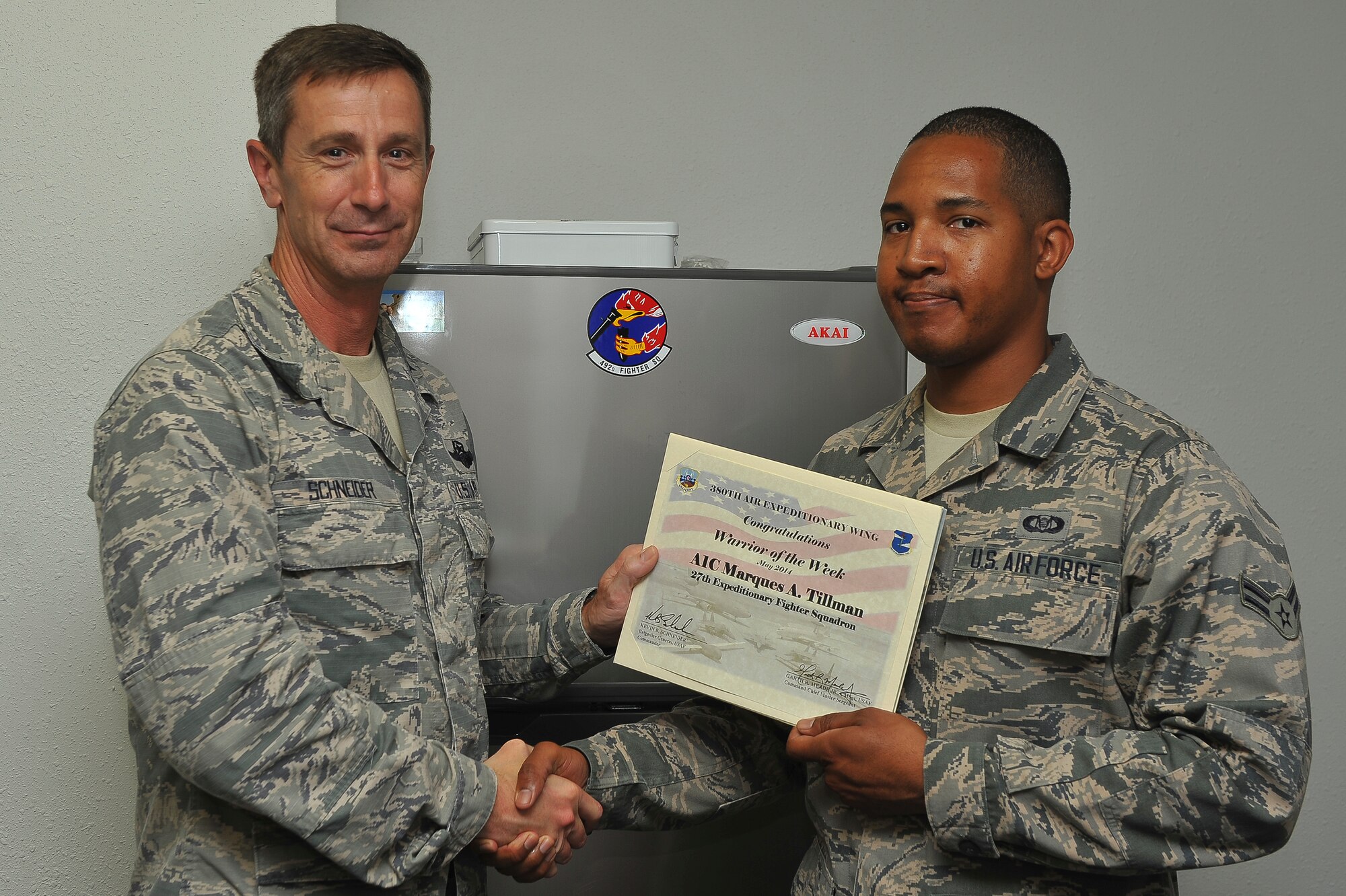 Air Force Brig. Gen. Kevin Schneider, 380th Air Expeditionary Wing commander, presents Airman 1st Class Marques Tillman, a 27th Expeditionary Fighter Squdron aviation resource manager, with the warrior of the week certificate at an undisclosed location in Southwest Asia, May 21, 2014. Tillman is a native of Homestead, Fla., and is deployed from Langley Air Force Base, Va. (U.S. Air Force photo by Tech. Sgt. Russ Scalf/Released)
