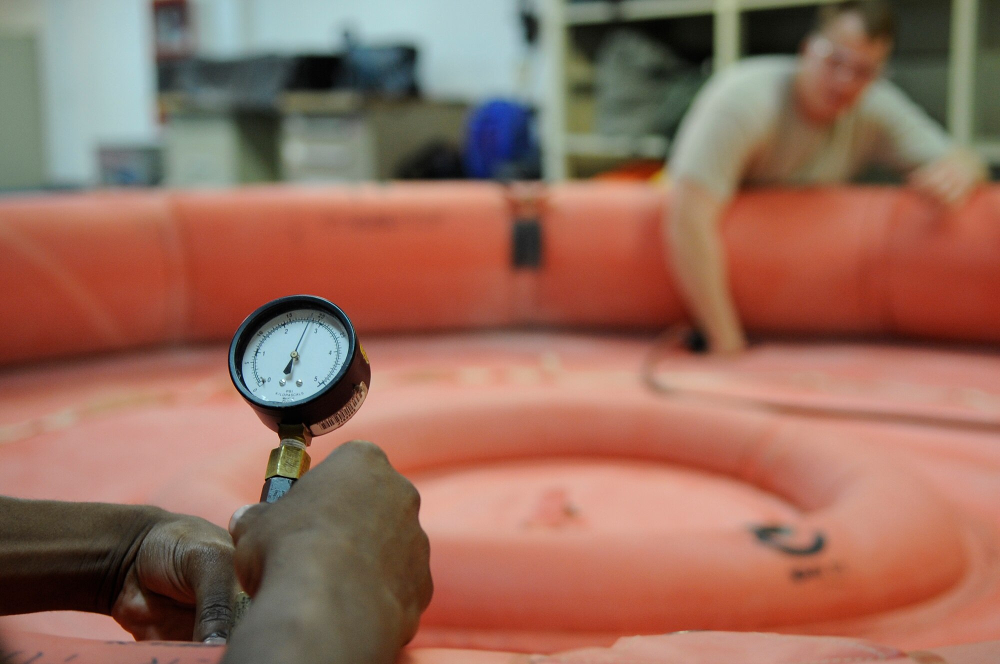U.S. Air Force Senior Airman Isaiah Sigler, 18th Operations Support Squadron aircrew flight equipment specialist, checks the pressure of a twenty-man raft as Senior Airman Zachary Gribble, 18th OSS aircrew flight equipment specialist, inflates it to test for leaks and serviceability on Kadena Air Base, Japan May 21, 2014. The 18th OSS aircrew flight equipment maintains parachutes, life preservers, survival kits and life-sustaining equipment for more than 80 aircraft. (U.S. Air Force photo by Senior Airman Marcus Morris)