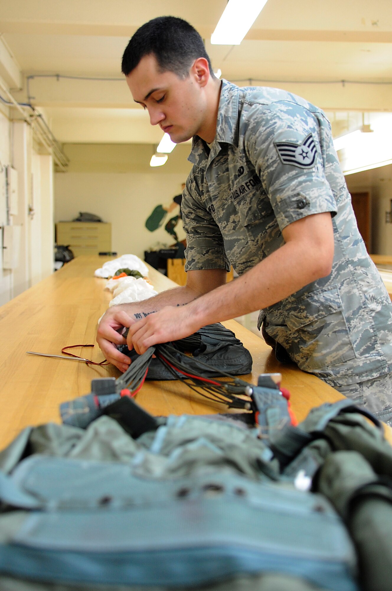 U.S. Air Force Staff Sgt. Travis Crawford, 18th Operations Support Squadron aircrew flight equipment specialist, packs a back-style emergency parachute on Kadena Air Base, Japan, May 21, 2014. The parachute is stored on heavy aircraft such as MC-130P Combat Shadows for emergency evacuation. (U.S. Air Force photo by Senior Airman Marcus Morris)