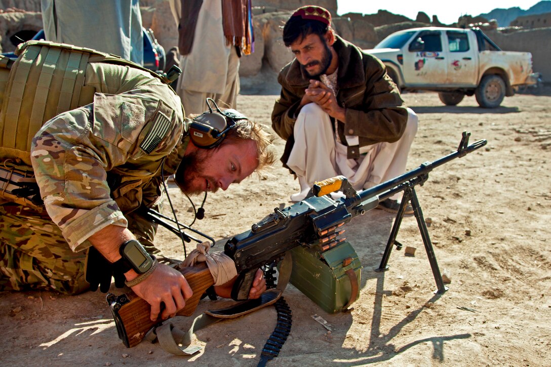 A coalition force member assists an Afghan local police officer with weapons maintenance during an operation to teach record keeping in the village of Khost in Afghanistan's Farah province, Nov. 3, 2012.  
