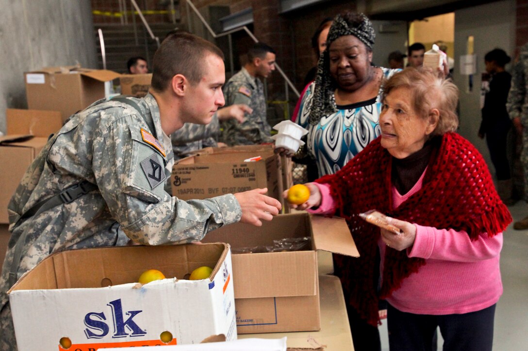 Army Spc. Anthony Monte helps a woman displaced by Hurricane Sandy at an emergency shelter at the Werblin Recreation Center in Piscataway Township, N.J., Oct. 29, 2012. Monte is assigned to the 50th Infantry Brigade Combat Team, New Jersey Army National Guard.  
