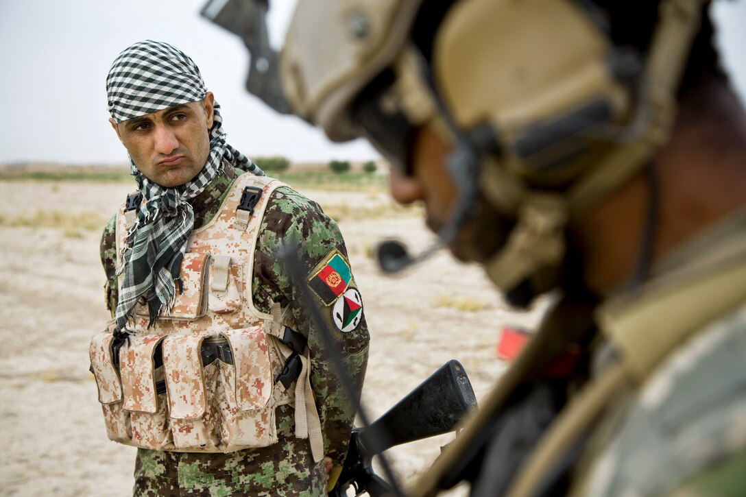 An Afghan soldier watches a coalition force member use his radio during an Afghan-led security patrol to deny the enemy freedom of movement in Khak-E-Safed in Afghanistan's Farah province, Oct. 30, 2012. Afghan forces have been taking the lead in security operations, with coalition forces as mentors, to bring security and stability to the country's residents.  
