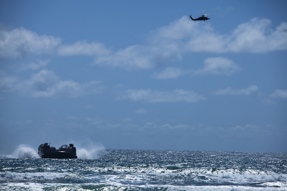 A landing craft air cushion transports vehicles and personnel from the 11th Marine Expeditionary Unit as an MH-60S Knighthawk flies overhead during ship-to-shore operations as part of Composite Training Unit Exercise (COMPTUEX) at Camp Pendleton, Calif., May 20, 2014. COMPTUEX serves as the second at-sea period for the 11th MEU, in which the unit will focus on the enabling and supporting functions necessary for success during full mission profile operations during the upcoming deployment. (U.S. Marine Corps photo by Cpl. Jonathan R. Waldman/Released)