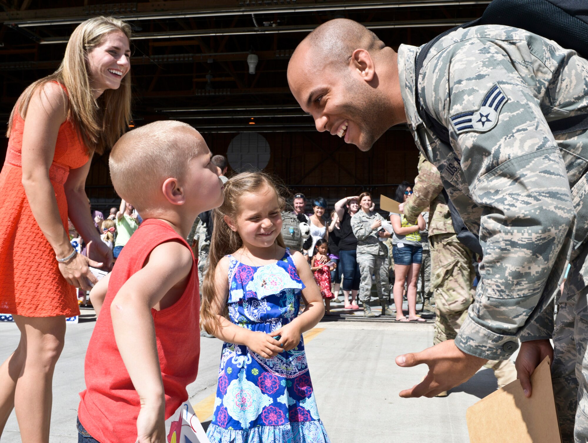 Senior Airman Decoltius Dickerson, 726th Air Control Squadron, returns from deployment to his wife and children at a celebration at the Mountain Home Air Force Base flightline, May 23, 2014, at the base in Southwestern Idaho. After a hello kiss to his daughter, Dickerson’s son asks when they’re going to Disney Land, which resulted in a mixed-emotional situation, and a memorable homecoming for the Dickerson family. 'Hardrock' Airmen provided time critical battle management command and control using sensors and communication located across Afghanistan. (U.S. Air Force photo by Master Sgt. Kevin Wallace/RELEASED)