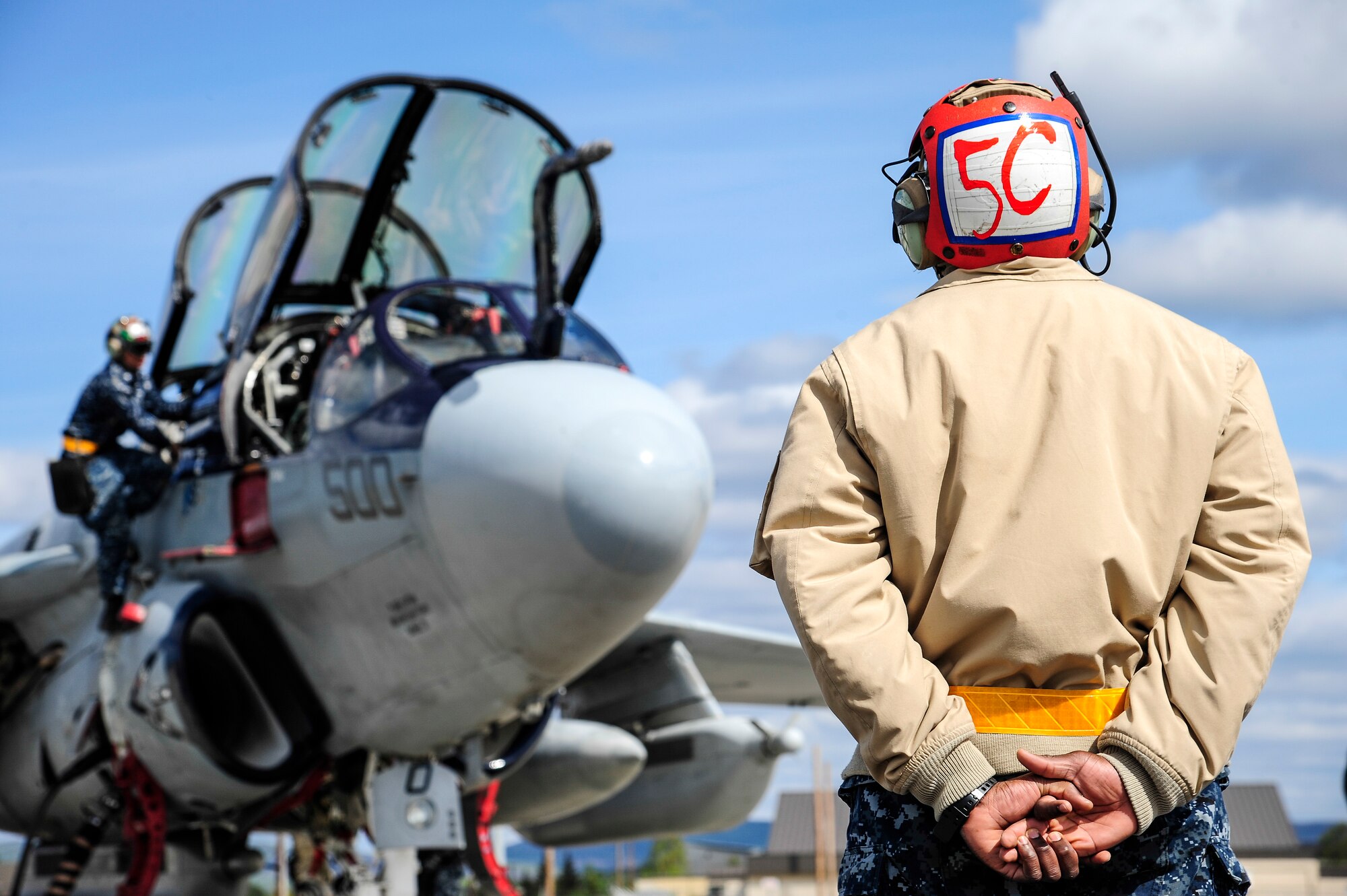 A U.S. Navy EA-6B Prowler crew chief from the Electronic Attack Squadron 142, Naval Air Station Whidbey Island, Oak Harbor, Wash., stands by as other crew chiefs perform preflight procedures during RED FLAG-Alaska 14-1 May 21, 2014, Eielson Air Force Base Alaska. The Prowler carries out missions by jamming enemy radar systems and gathering radio intelligence on enemy air defense systems. (U.S. Air Force photo by Senior Airman Zachary Perras/Released)