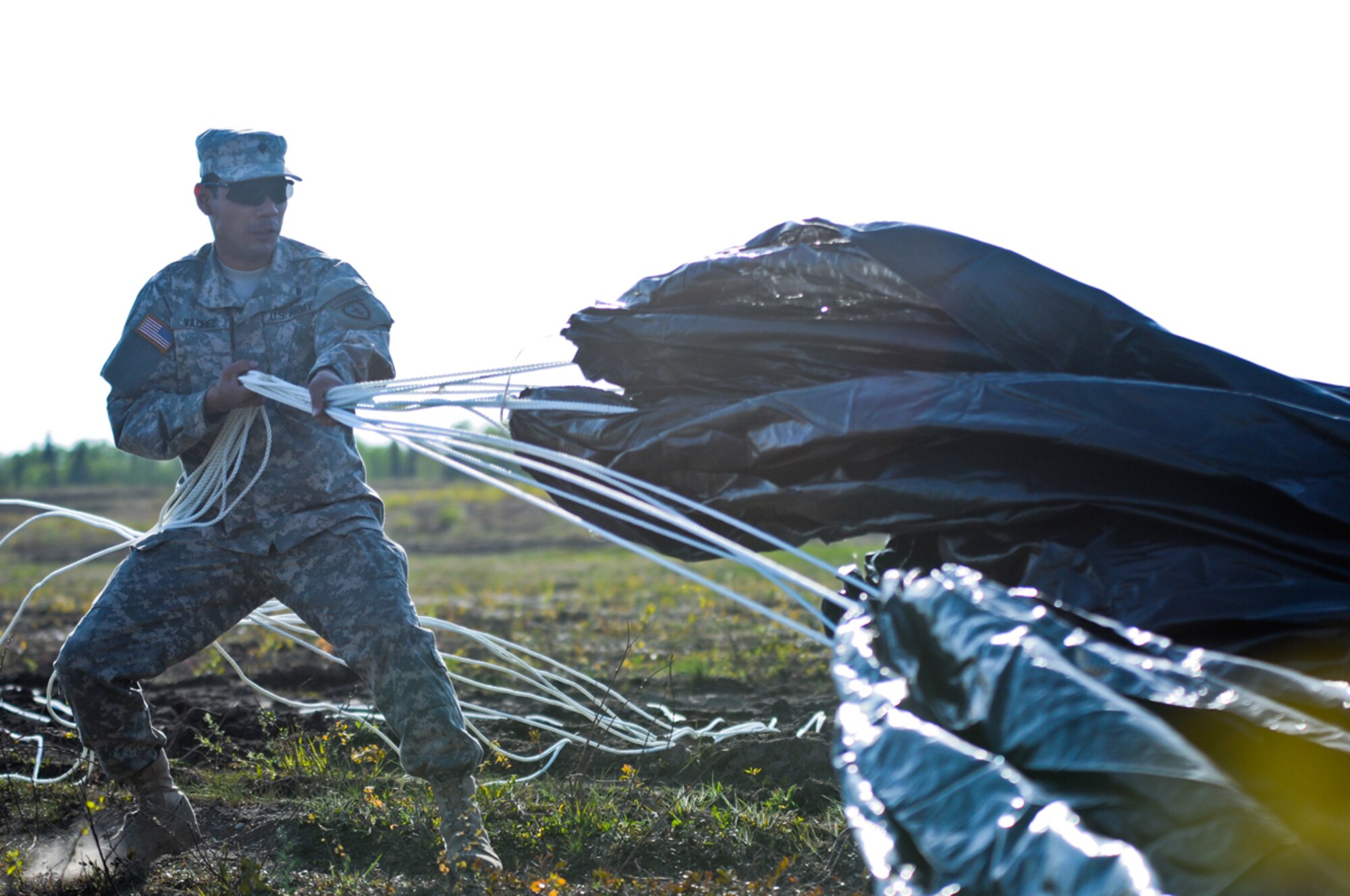 A paratrooper with the 4th Quartermaster Company, assigned to the 725th Brigade Support Battalion, 4th Infantry Brigade Combat Team (Airborne), 25th Infantry Division, recovers equipment from a supply pallet that was dropped using the Low-Cost, Low Velocity (LCLV) parachute delivery system onto Malemute Drop Zone at Joint Base Elmendorf-Richardson, Alaska, May 16. This is the first time equipment has been dropped into Alaska using this type of delivery system. The LCLV can safely drop a supply pallet weighing up to and including 2,200 pounds into remote locations such as those found in Afghanistan, or Alaska. (U.S. Army photo by Sgt. Eric-James Estrada)