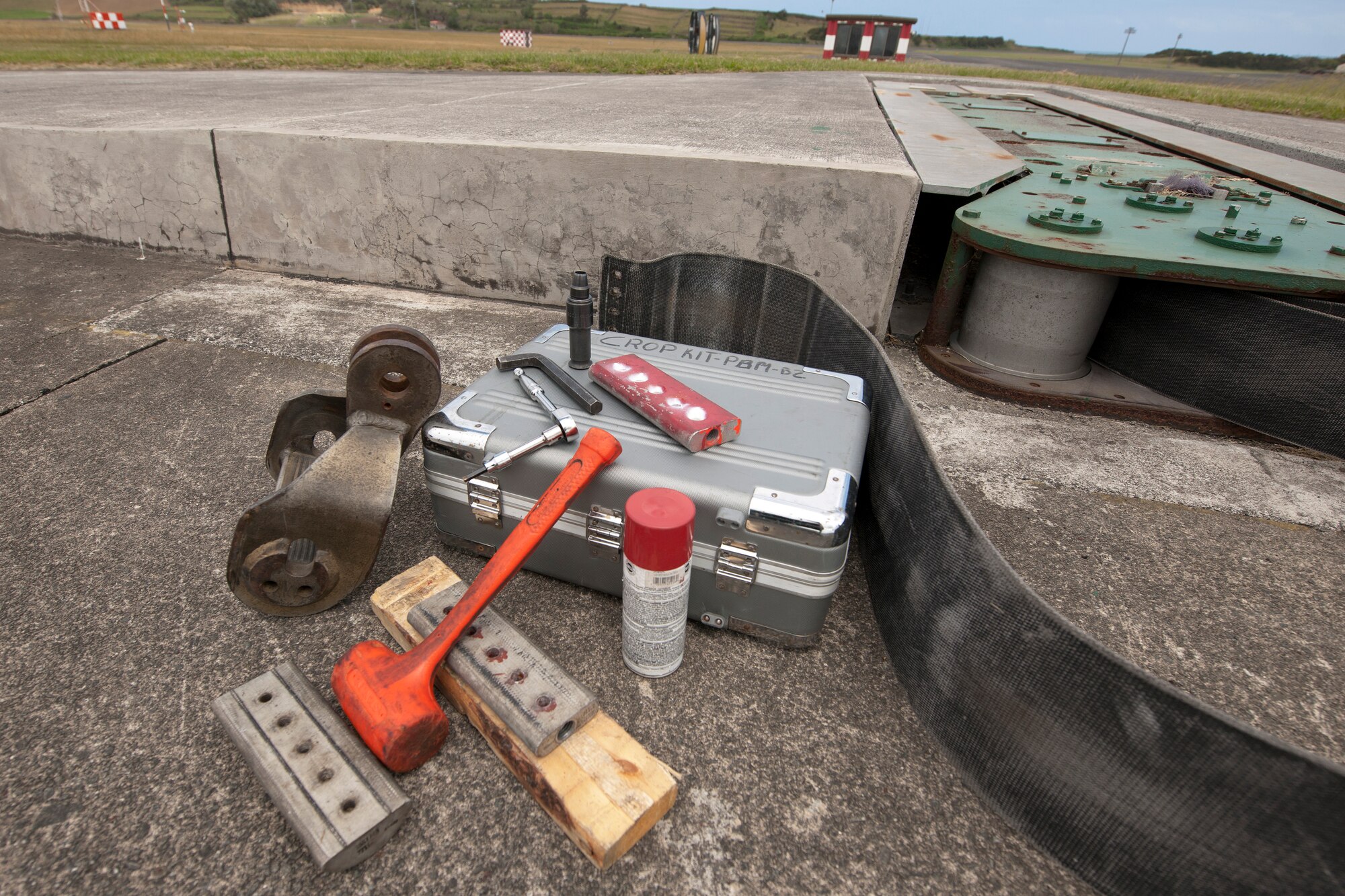 U.S. Air Force power production technicians from the 65th Civil Engineer Squadron perform a semiannual tape crop on an aircraft arresting system May 20, 2014, at Lajes Field, Azores, Portugal. The crop is to remove the exposed tape that has been damaged by the elements. The power production office maintains the AAS to ensure the integrity of the system. In the event of an inflight emergency the AAS will stop an aircraft that is equipped with a tail hook to prevent loss of aircraft and life. (U.S. Air Force photo by Tech. Sgt. Paul Villanueva II/Released)