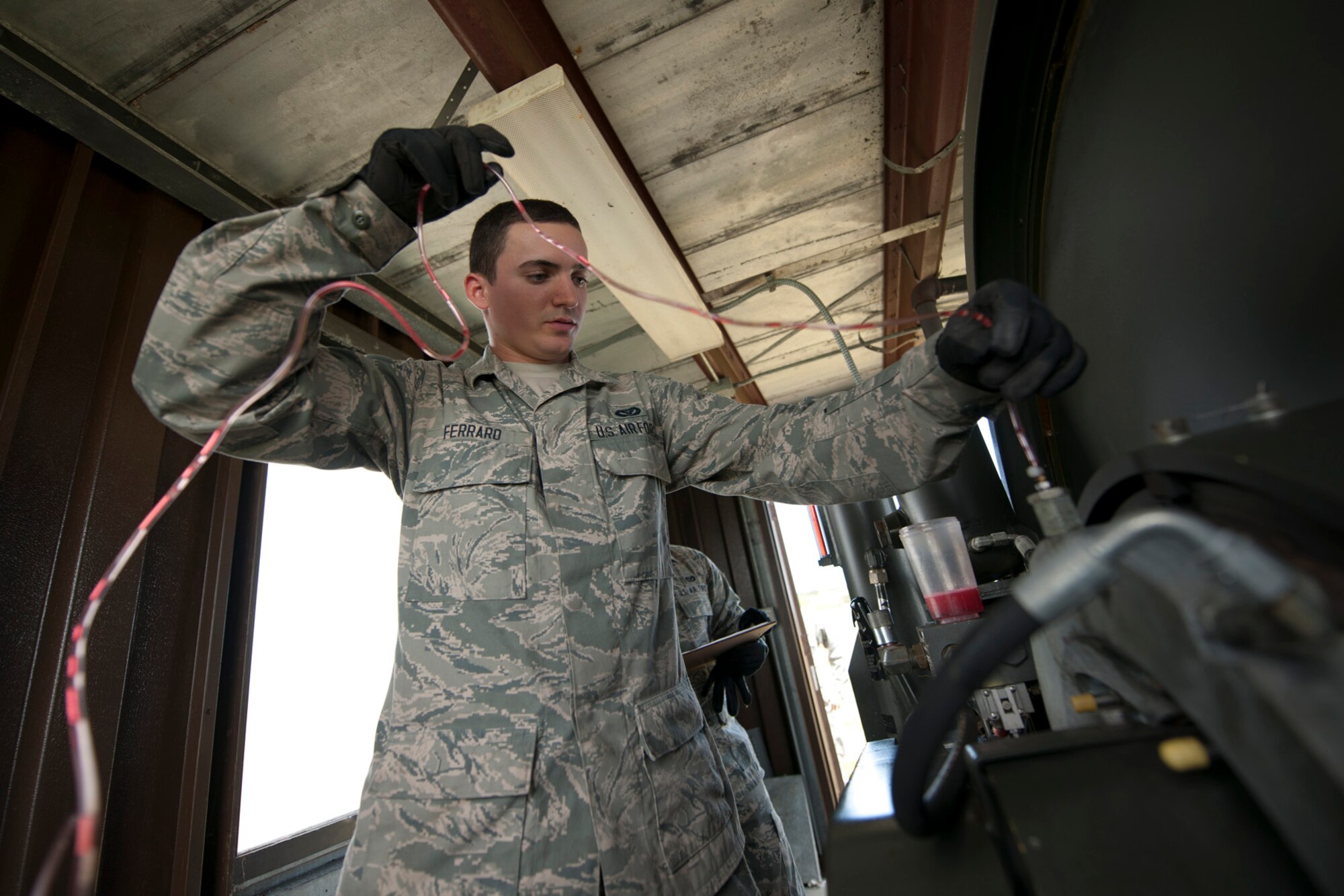 U.S. Air Force Airman 1st Class Andrew Ferraro, 65th Civil Engineer Squadron power production technician, attaches the hydraulic bleeding tube to the brakes of an aircraft arresting system May 20, 2014, Lajes Field, Azores, Portugal. Ferraro performed a weekly preventive maintenance inspection and a semiannual tape crop. The power production office maintains the AAS to ensure the integrity of the system. In the event of an inflight emergency the AAS will stop an aircraft that is equipped with a tail hook to prevent loss of aircraft and life. (U.S. Air Force photo by Tech. Sgt. Paul Villanueva II/Released)