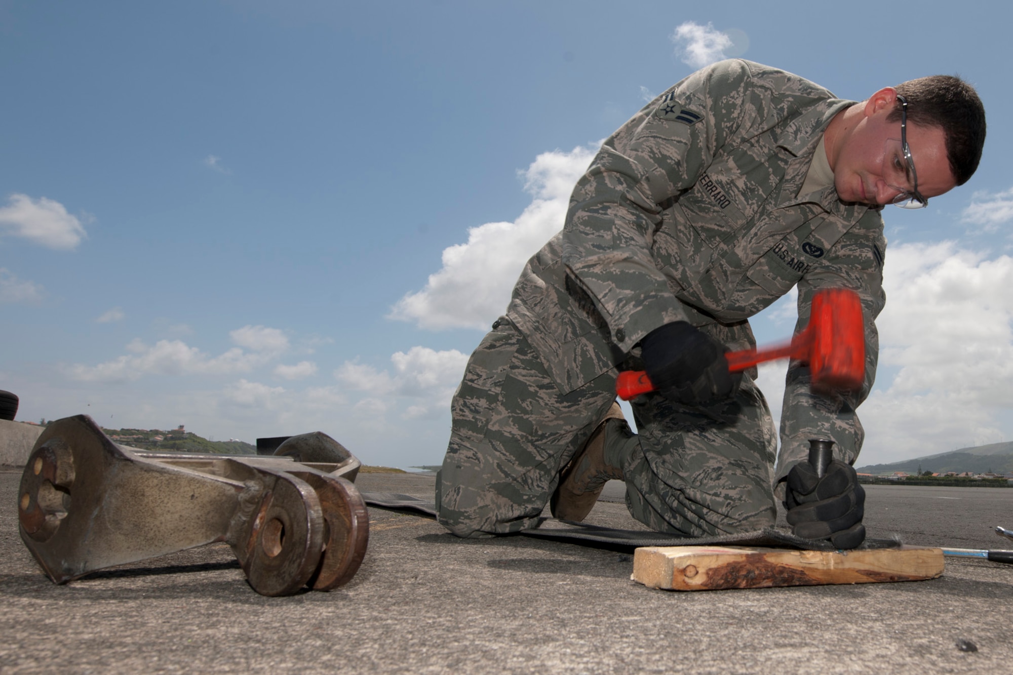 U.S. Air Force Airman 1st Class Andrew Ferraro, 65th Civil Engineer Squadron power production technician, punctures holes into the tape of an aircraft arresting system during a semiannual tape crop May 20, 2014, at Lajes Field Azores, Portugal. The power production office maintains the AAS to ensure the integrity of the system. In the event of an inflight emergency the AAS will stop an aircraft that is equipped with a tail hook to prevent loss of aircraft and life. (U.S. Air Force photo by Tech. Sgt. Paul Villanueva II/Released)