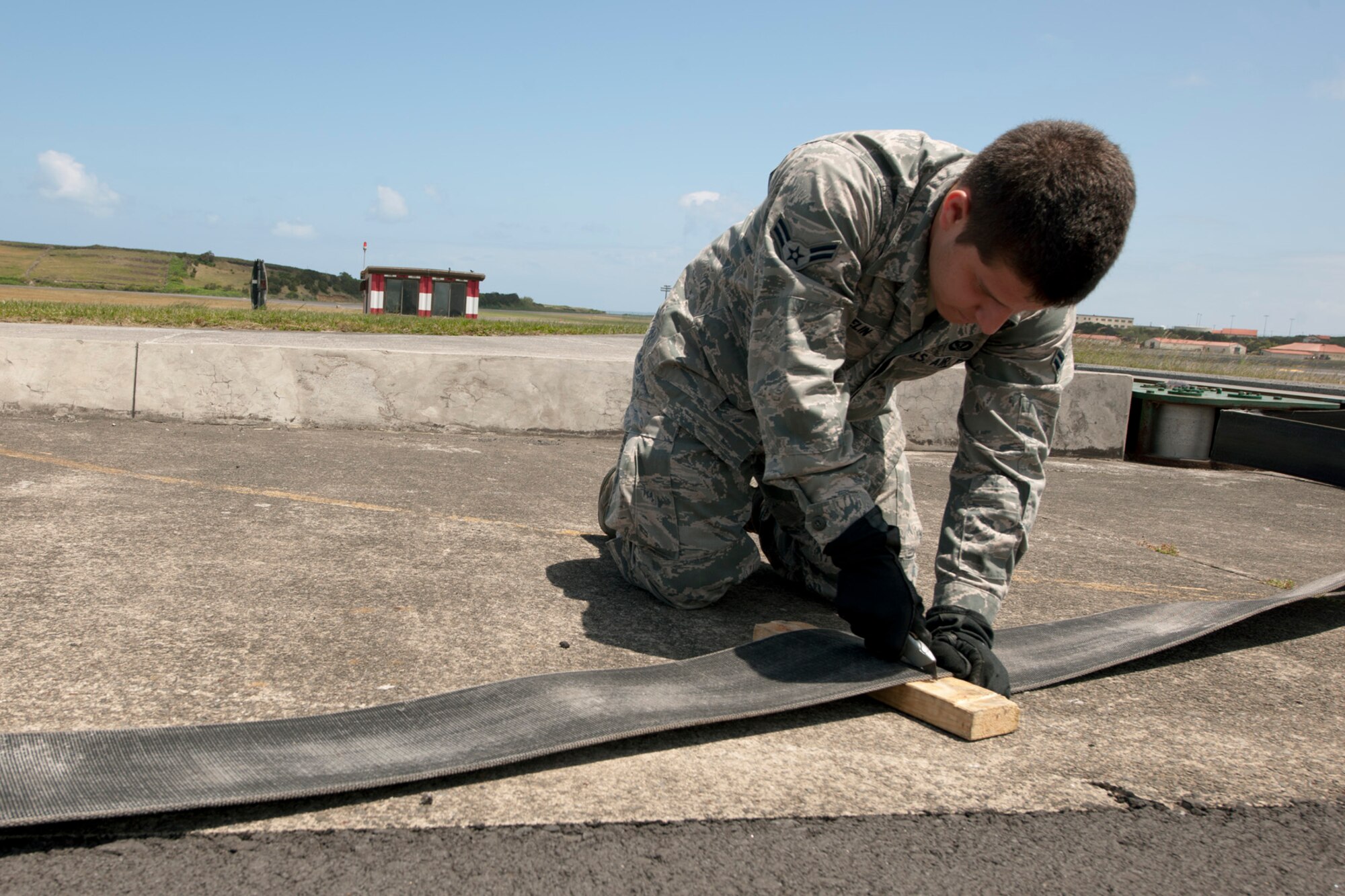 U.S. Air Force Airman 1st Class Daniel Gosselin, 65th Civil Engineer Squadron power production technician, cuts damaged tape from an aircraft arresting system during a semiannual tape crop May 20, 2014, at Lajes Field, Azores, Portugal. The crop is to remove the exposed tape that has been damaged by the elements. The power production office maintains the AAS to ensure the integrity of the system. In the event of an inflight emergency the AAS will stop an aircraft that is equipped with a tail hook to prevent loss of aircraft and life. (U.S. Air Force photo by Tech. Sgt. Paul Villanueva II/Released)