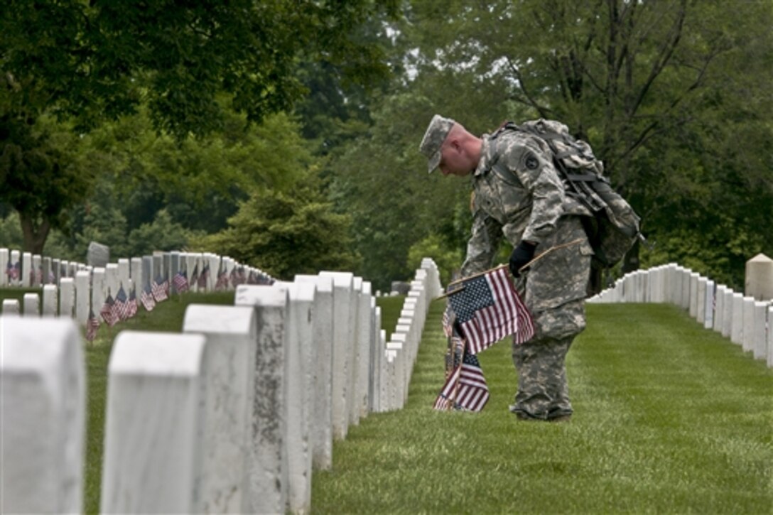 Soldiers assigned to the 3rd U.S. Infantry Regiment, known as "The Old Guard," place flags in front of  gravesites during "Flags In," an annual event before Memorial Day, at Arlington National Cemetery, Va., May 22, 2014.