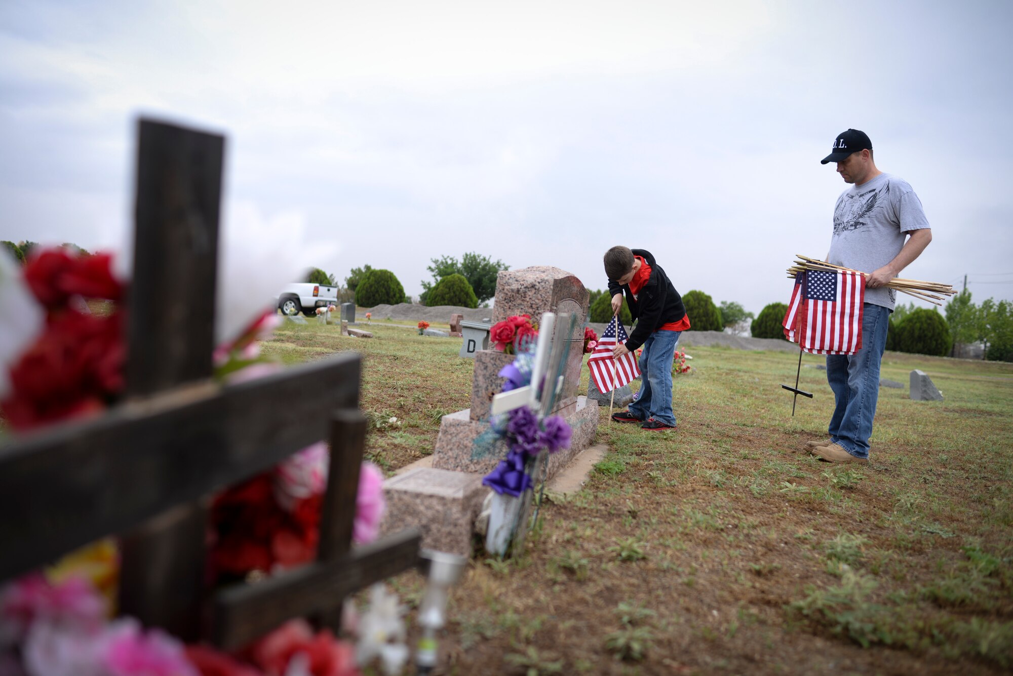 ALTUS, Okla. – U.S. Air Force Master Sgt. Chris Lauderback and his 9-year-old son place a U.S. flag beside the tombstone of a deceased U.S. service member at the Altus City Cemetery, May 24, 2014. This is the second year that the Lauderback family has placed flags together on Memorial Day weekend. (U.S. Air Force photo by Staff Sgt. Nathanael Callon/Released)