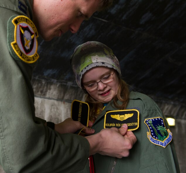 U.S. Air Force Capt. Matt Tanis, 48th Air Expeditionary Group F-15C Eagle pilot, presents flight wings to Kolbrun Erlendsdottir, 11, at the end of the pilot-for-a-day program May 23, 2014, at Keflavik International Airport in Iceland. Airmen deployed with the 48th AEG took time out of their day to brighten the lives of the two children who have been struggling with serious long-term illnesses. (U.S. Air Force photo by Tech. Sgt. Benjamin Wilson/Released)