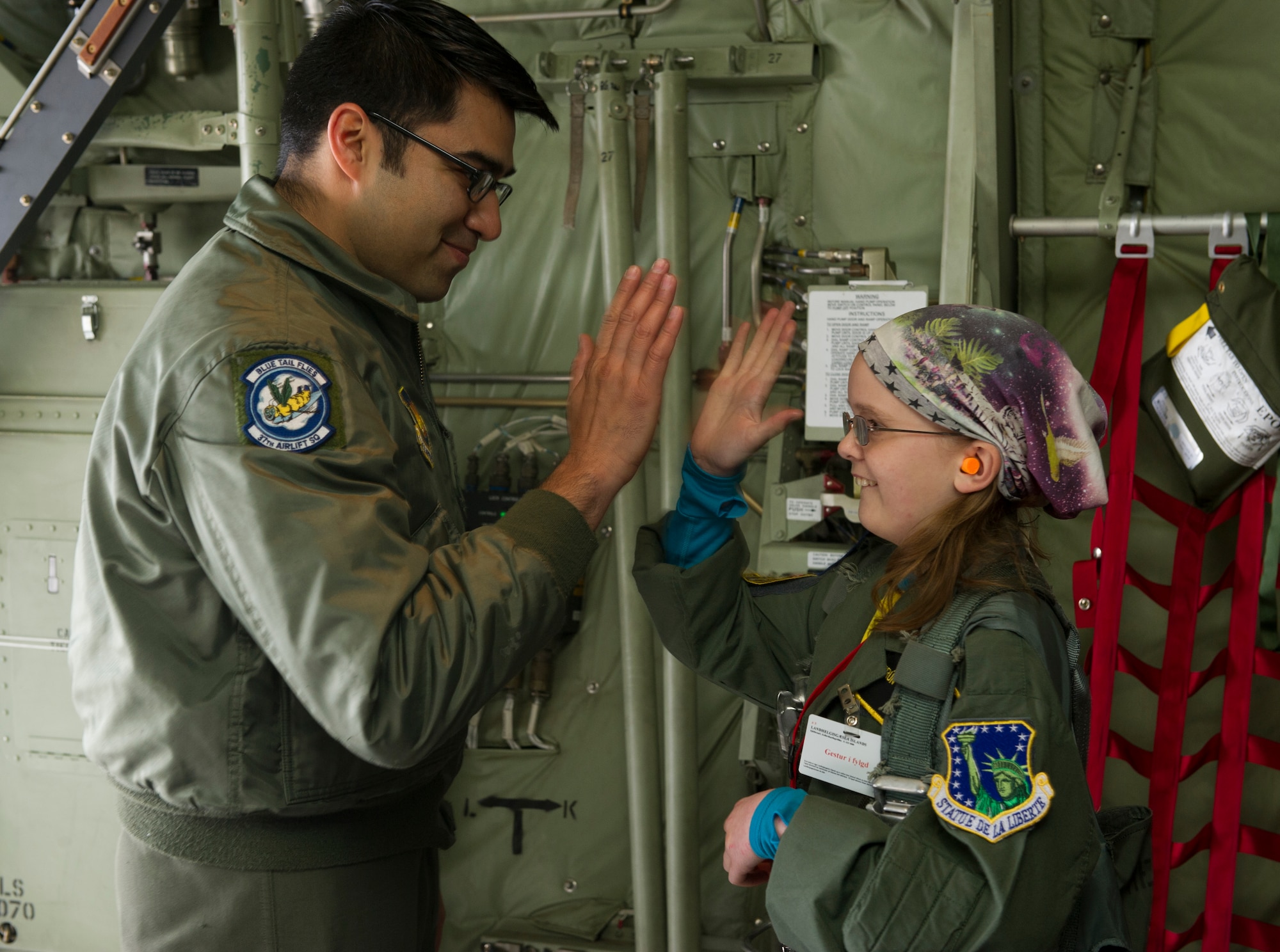 KEFLAVIK, Iceland -- Staff Sgt. Luis Murillo, 48th Air Expeditionary Group C-130J Super Hercules loadmaster, high fives Kolbrun Erlendsodottir, 11, as during the pilot-for-a-day program at Keflavik International Airport May 23, 2014. Airmen deployed with the 48th AEG took time out of their day to brighten the lives of two children who have been struggling with serious long-term illnesses. (U.S. Air Force photo/Tech. Sgt. Benjamin Wilson)(Released)