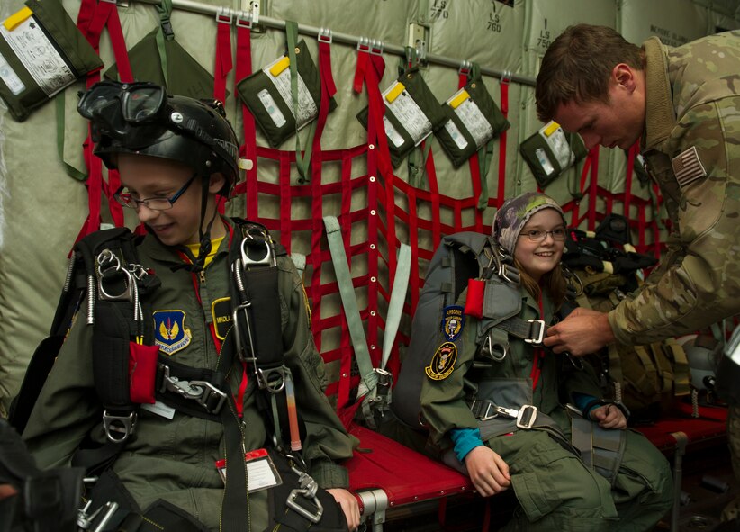 U.S. Air Force Staff Sgt. Zachary, 48th Air Expeditionary Group pararescueman, helps Kolbrun Erlendsdottir, right, 11, and Mikolaj Chojecki, 14, suit up in pararescue equipment during the pilot-for-a-day program May 23, 2014, at Keflavik International Airport in Iceland. Airmen deployed with the 48th AEG took time out of their day to brighten the lives of the two children who have been struggling with serious long-term illnesses. (U.S. Air Force photo by Tech. Sgt. Benjamin Wilson/Released) 