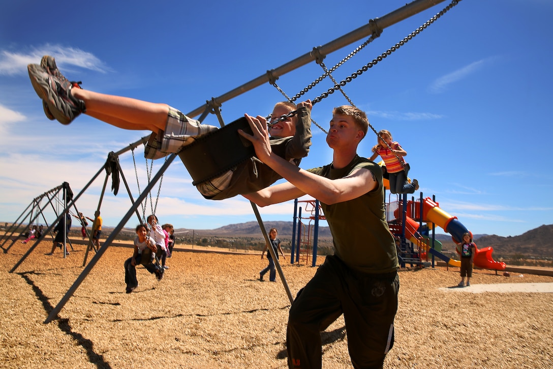 Cpl. Perry Baxter, squad leader, 3rd Battalion, 4th Marines, pushes a student on the swing during the unit's bimonthly visit as part of the Adopt-a-School program April 3, 2014. The Marines visit the school twice a month, building bonds with kids through play and learning.