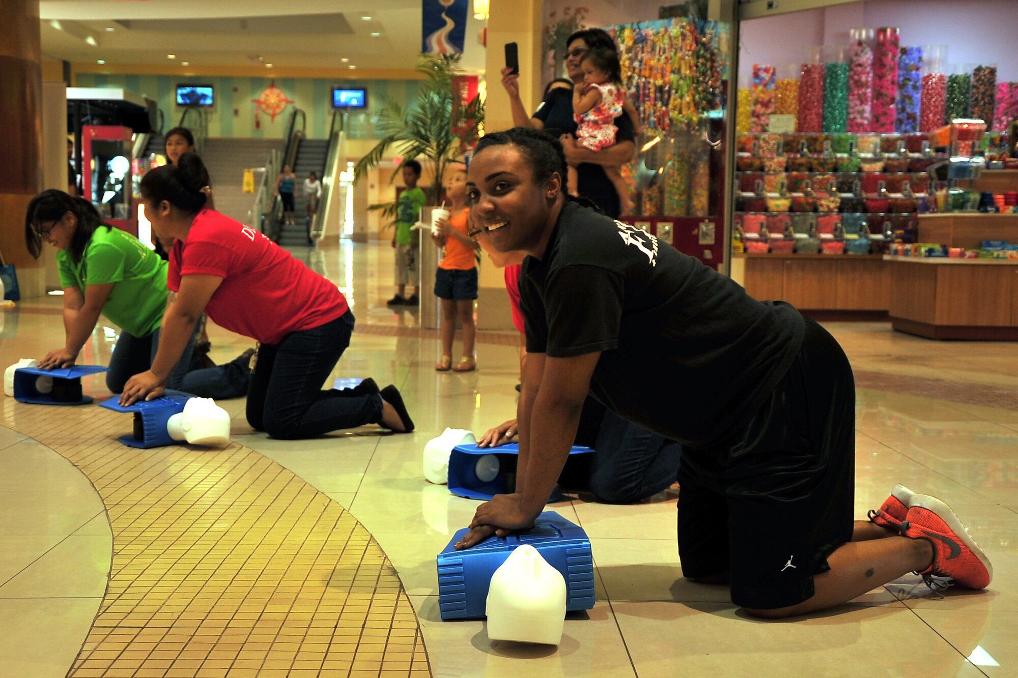 Airman Golden Wallace, 36th Civil Engineer Squadron firefighter, participates in a CPR-themed flash mob at the Agana Shopping Center, Guam, May 18, 2014. First responders from around Guam participated in the event during a public health fair in recognition of Emergency Medical Services Week to bring awareness to how CPR could help save lives. (U.S. Air Force photo by Staff Sgt. Melissa B. White/Released)