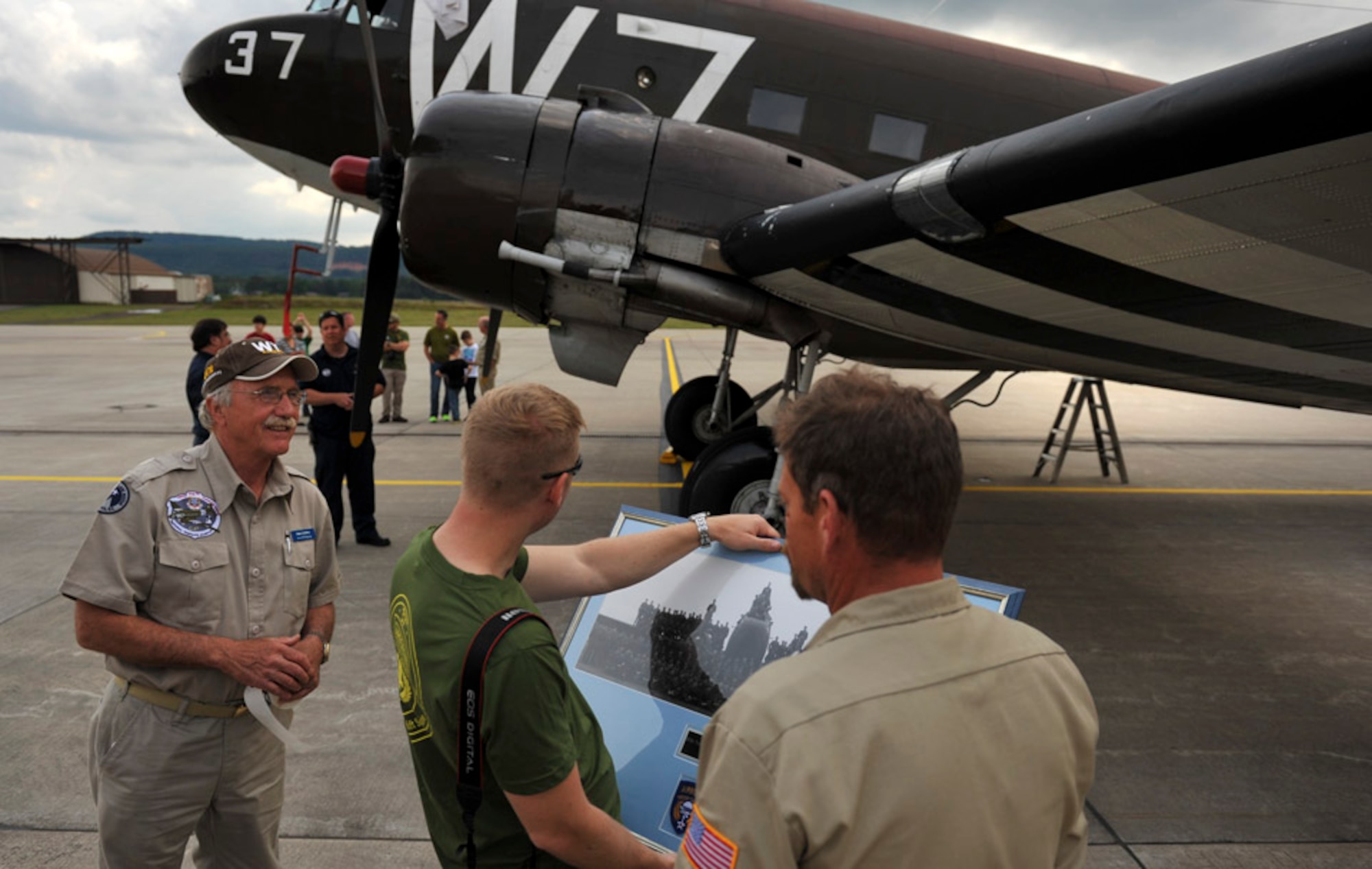 A pilot from the 37th Airlift Squadron holds a group photo from 1944 of the 37th Troop Carrier Squadron taken in front of the same Douglas C-47 Skytrain, designated Whiskey 7, just after landing the aircraft at Ramstein Air Base, May 26, 2014. Whiskey 7 was the lead carrier of 37th Troop Carrier Squadron that took part in dropping the 82nd Airborne Division near St. Mere Eglise, France during D-Day, June 6th, 1944. The historical aircraft landed in Ramstein before heading to Normandy to take part in commemoration events for the 70th Anniversary of D-Day. (U.S. Air Force photo/Staff Sgt. Sara Keller)