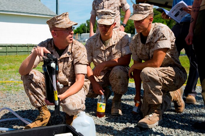 Master Sgt. Kevin Morris (left), project officer for Marine Corps water systems at Marine Corps Systems Command, holds up the filtration system for the small unit water purifier prototype during a demonstration for Marines with 2nd Marine Logistics Group aboard Camp Lejeune, North Carolina May 9. The prototype is designed for platoon-level units and smaller. The system weighs approximately 75 pounds and allows a platoon-size element of Marines to purify 7-10 gallons of water per hour from local water sources.