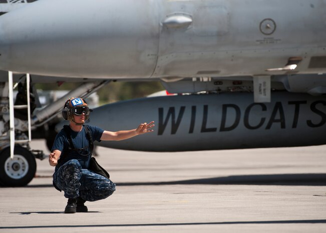 U.S. Navy Airman Michael Sinclair, plane captain assigned to Strike Fighter Squadron 131, Naval Air Station Oceana, Va. signals to start the auxiliary power unit while preparing an F/A-18C Hornet for takeoff during Green Flag 14-07, May 21, 2014, at Nellis Air Force Base Nev. Green Flag exercises give air and ground crews from different branches of the U.S. military and allied nations the opportunity to practice air-to-ground combat scenarios together. (U.S. Air Force photo by Airman 1st Class Thomas Spangler) 