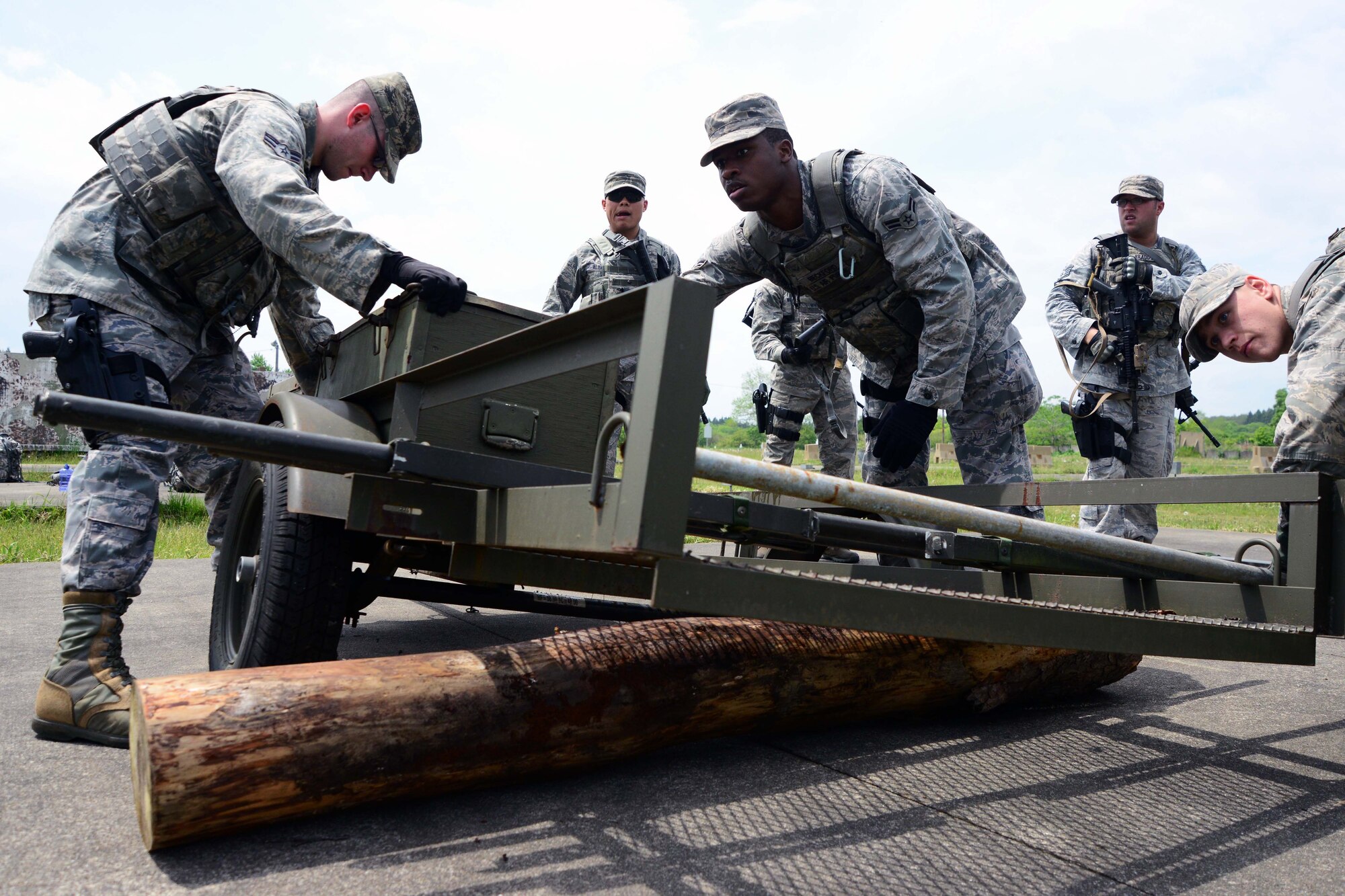 Members of the 35th Security Forces Squadron Special Reaction Team work together to transport equipment on a damaged trailer at Misawa Air Base, Japan, May 27, 2014. The exercise was one of many challenges the SRT faced in order to become qualified as team members with the 35 SFS. (U.S. Air Force photo/Senior Airman Derek VanHorn)
