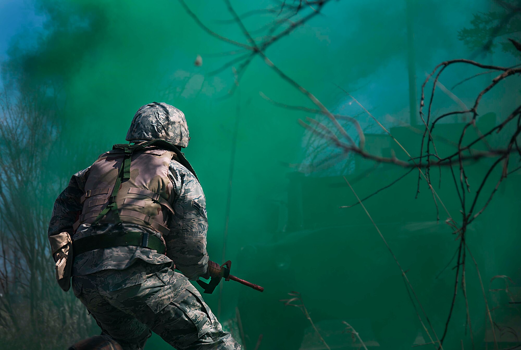 A member of the 5th Civil Engineer Squadron runs behind a smoke bomb during an exercise at Minot Air Force Base, N.D., May 21, 2014. The exercise was part of pre-deployment training. (U.S. Air Force photo/Airman 1st Class Lauren Pitts) 