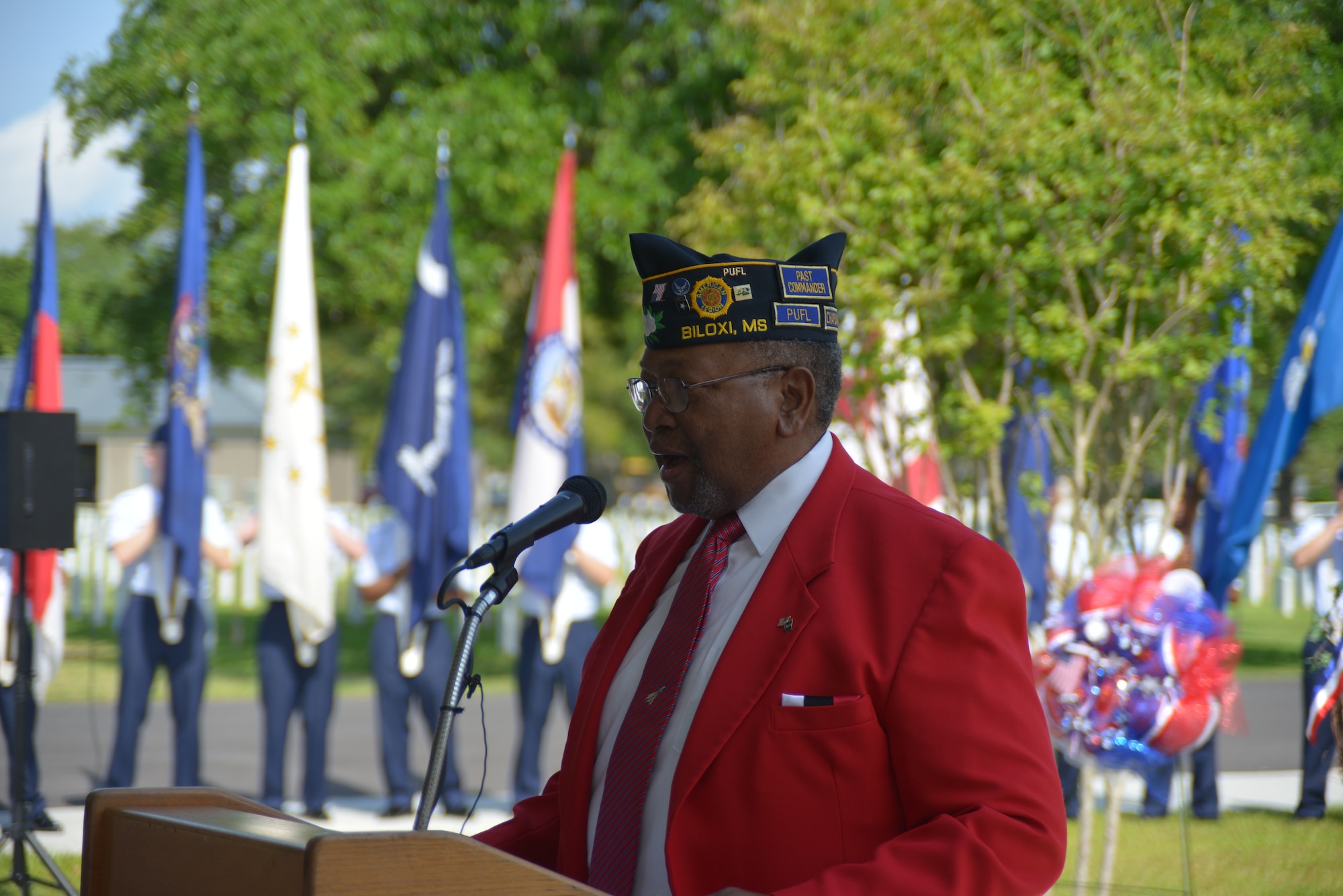 Retired Chief Master Sgt. Chris Moore sings “God Bless America” during a Memorial Day ceremony at the Biloxi National Cemetery May 26, 2014. Brig. Gen. Patrick Higby, 81st Training Wing commander, Keesler Air Force Base, Miss., was the keynote speaker for the event.  Higby spoke to more than 200 community representatives, veterans and family members about the many sacrifices made by veterans and the price of freedom today.   Airmen from the 81st Training Group holding the 50 state flags also participated in the event. (U.S. Air Force photo by Richard Meuse)