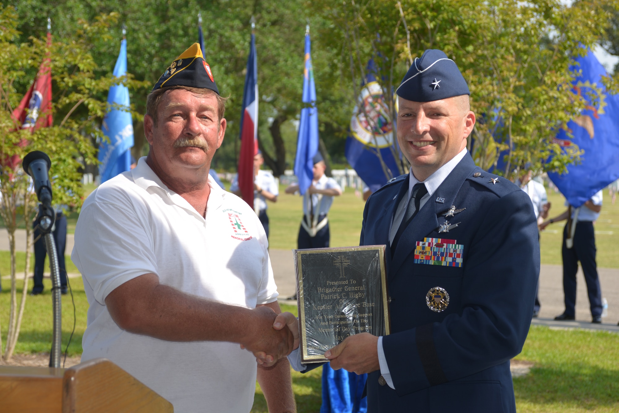 Jerry Miscavage, chairman of the Biloxi National Cemetery Memorial Day Committee, presents a plaque to Brig. Gen. Patrick Higby, 81st Training Wing commander, Keesler Air Force Base, Miss., for serving as the keynote speaker for the Memorial Day ceremony at the Biloxi National Cemetery May 26, 2014.  Higby spoke to more than 200 community representatives, veterans and family members attend about the many sacrifices made by veterans and the price of freedom today.  Airmen from the 81st Training Group holding the 50 state flags also participated in the event. (U.S. Air Force photo by Richard Meuse)