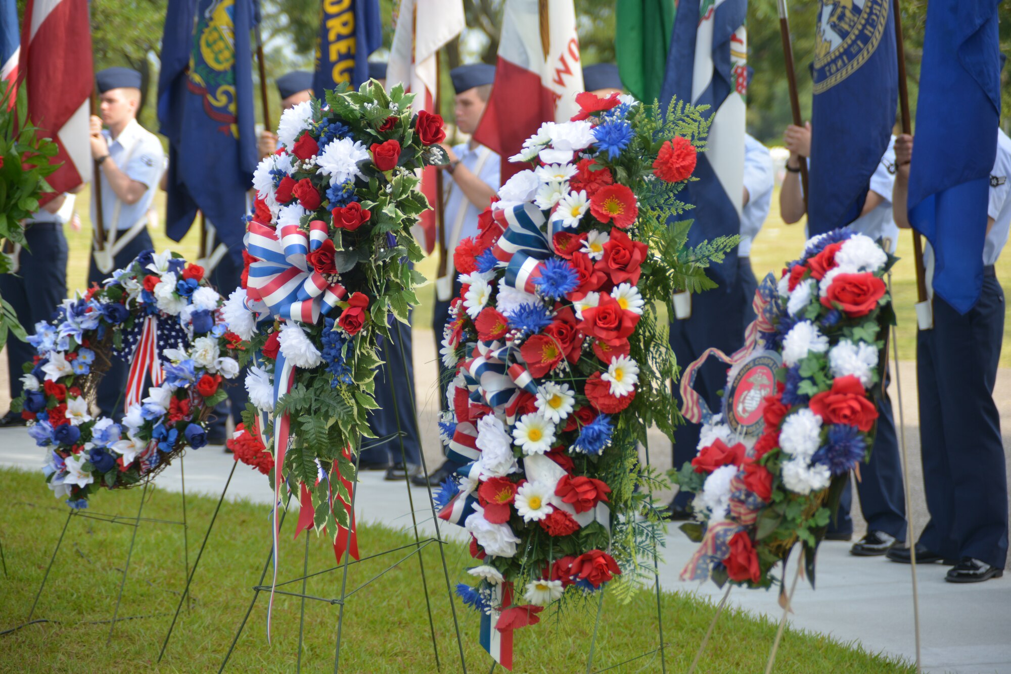 Wreaths from various veteran organizations are displayed in front of Airmen from the 81st Training Group, Keesler Air Force Base, Miss., holding the 50 state flags during a Memorial Day ceremony at the Biloxi National Cemetery May 26, 2014. Brig. Gen. Patrick Higby, 81st Training Wing commander, was the keynote speaker for the event.  Higby spoke to more than 200 community representatives, veterans and family members about the many sacrifices made by veterans and the price of freedom today.  (U.S. Air Force photo by Richard Meuse)