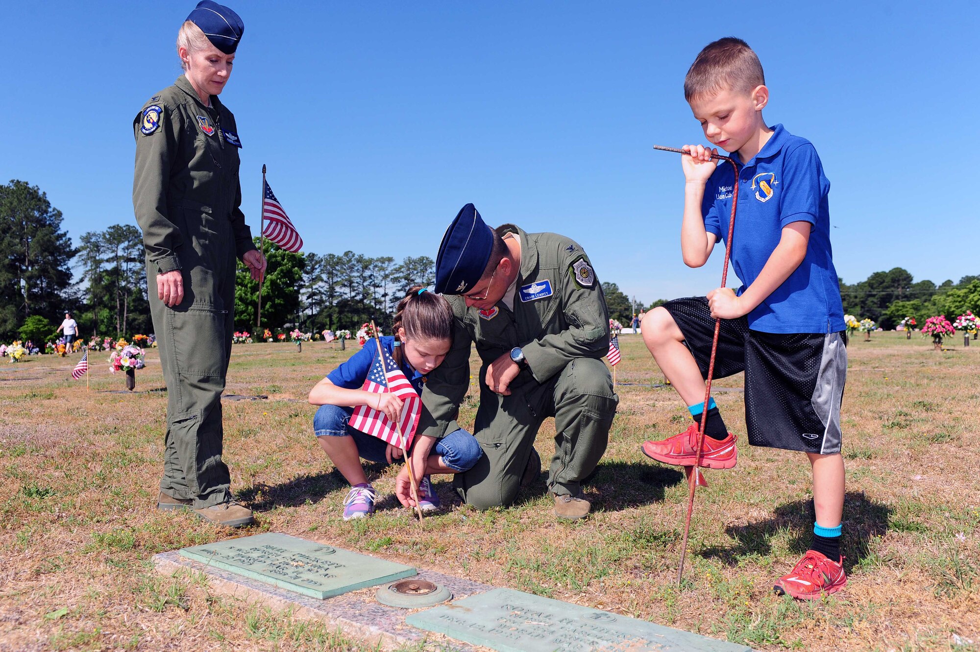 Col. Jeannie Leavitt, 4th Fighter Wing commander, and her husband Col. Craig Leavitt, Air Combat Command inspection team chief, assist their daughter with placing an American flag by a gravestone, May 24, 2014, at Wayne Memorial Park in Goldsboro, North Carolina. Flags were placed by prior Service member’s gravestones in remembrance of their service. (U.S. Air Force photo/Senior Airman John Nieves Camacho)