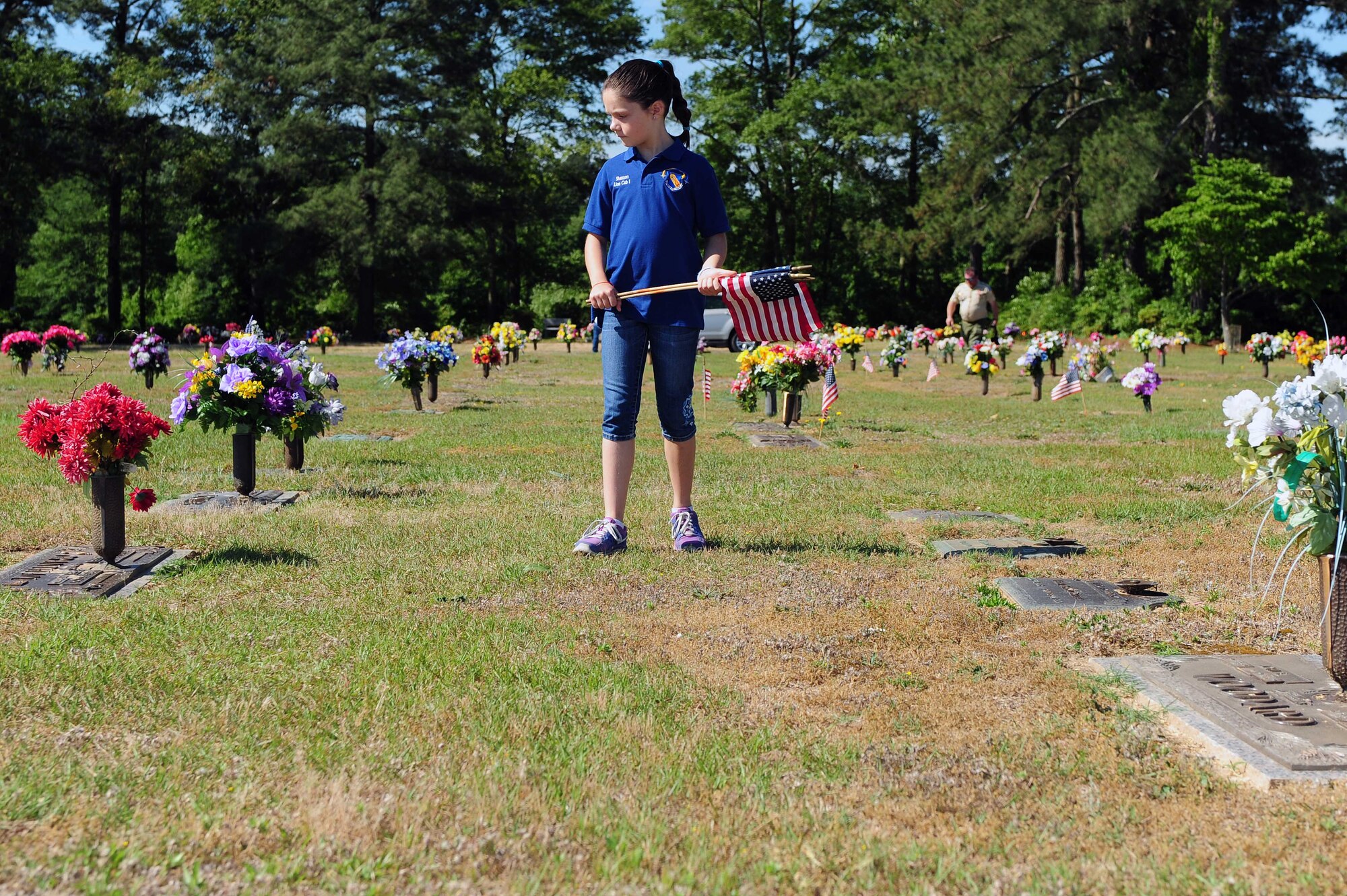 The daughter of Col. Jeannie Leavitt, 4th Fighter Wing commander, participates in the memorial flag setting event, May 24, 2014, at Wayne Memorial Park in Goldsboro, North Carolina. During Memorial Day weekend, the Leavitt family placed more than 50 flags on gravestones around the cemetery to honor veterans who served in the Armed Forces. (U.S. Air Force photo/Senior Airman John Nieves Camacho)