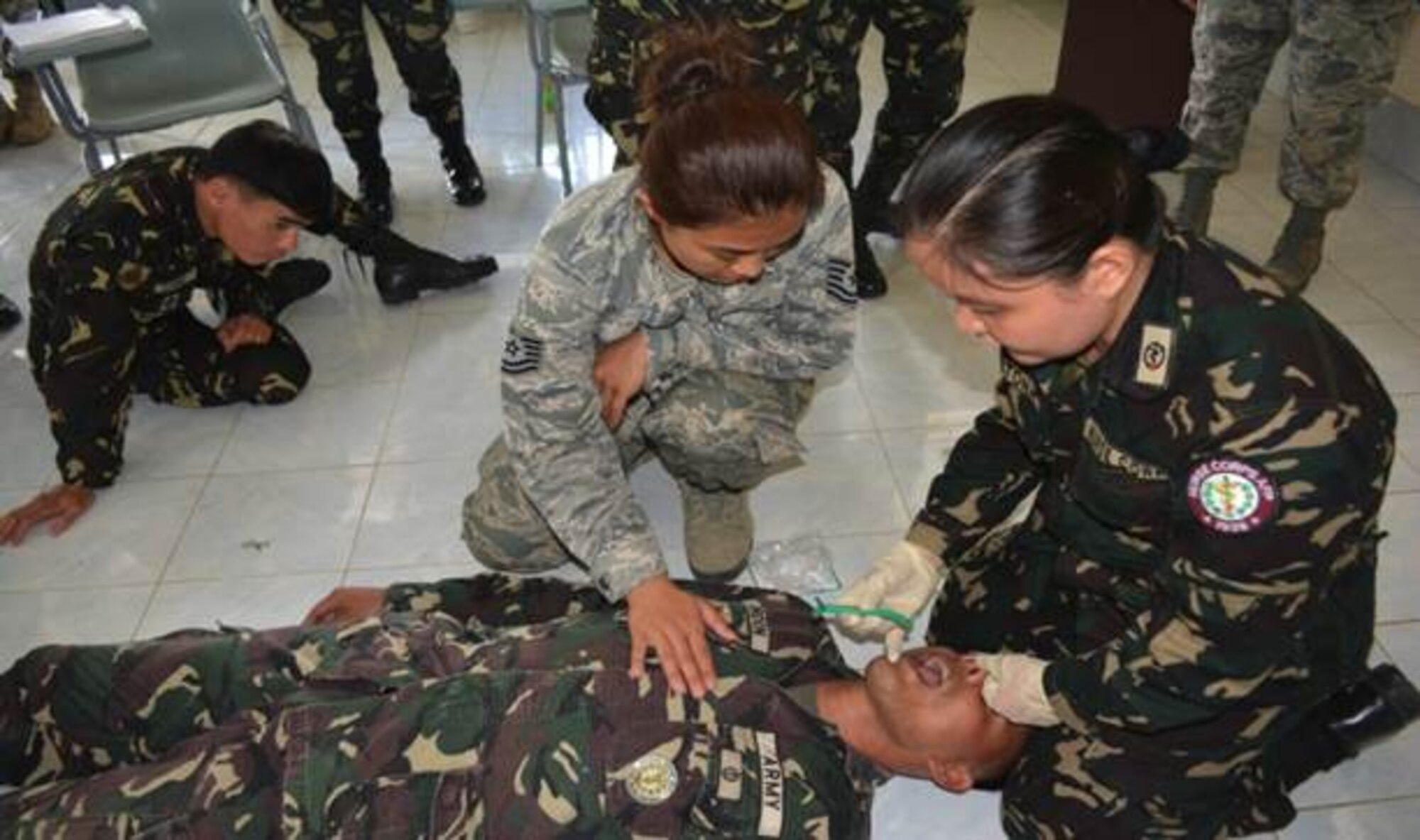 Tech. Sgt. Louise Albertine Sarabosing, center, a medical technician with the 624th Aeromedical Staging Squadron, Joint Base Pearl Harbor-Hickam, Hawaii, places her hand on a Philippine Army members chest calm them while a nurse (unknown) with the Philippine military, right, inserts a nasopharyngeal airway (NPA), into another trainee’s nose, Cavite, Philippines, Mar. 25, 2014. (Courtesy photo/Guam Army National Guard)